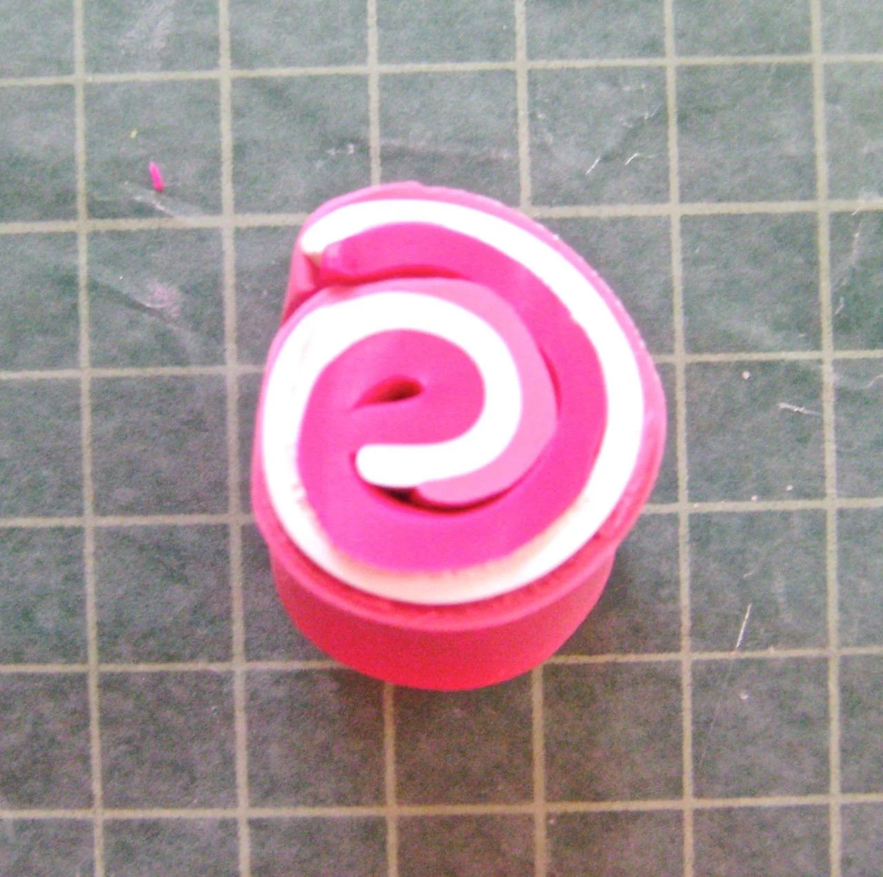 step 1 - To achieve the dark pink color, roll thin sheets of Fuchsia, Ballerina, and White clay together. Slice a .50” wide piece from the roll and run it through the conditioning machine until you reach the blended shade you like.