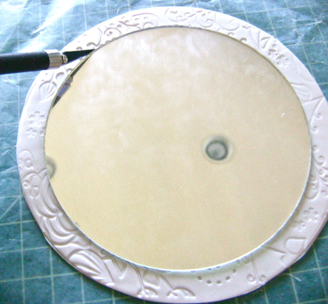 step 8 - Center the mirror on the textured circle. With a craft knife, run along the edge of the mirror cutting a frame in which the mirror will rest. Remove the mirror.