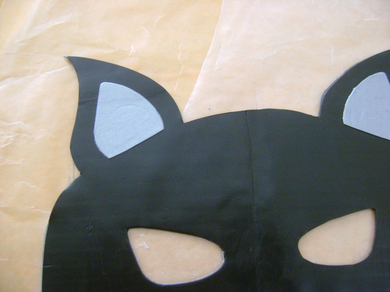 step 4 - Place the mask template on the joined pieces. Use a craft knife to cut out the mask shape. Use the template’s ears to cut silver ear linings from the clay. Remove a portion of the bottoms and place the linings on the mask.