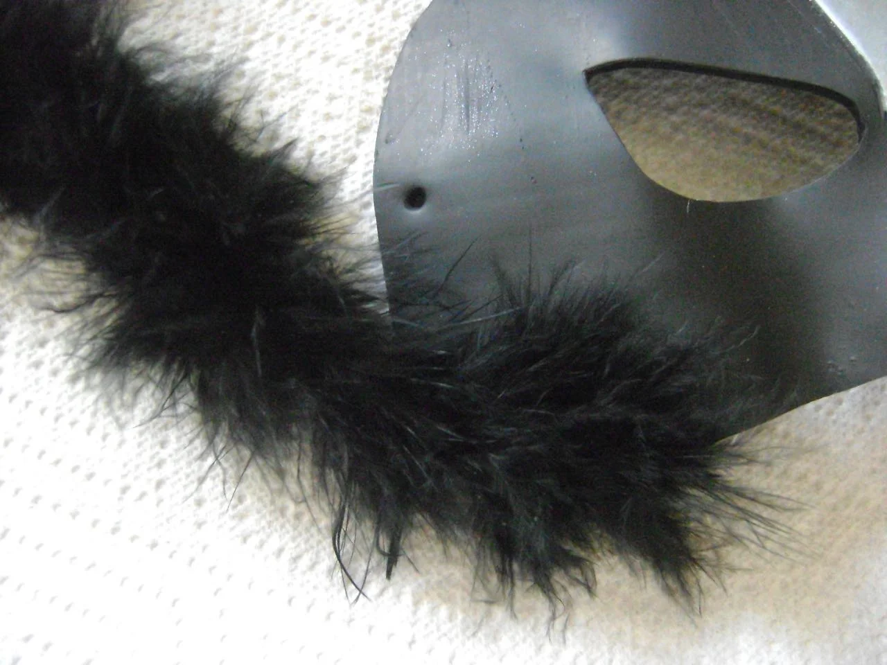 step 11 - Hot glue fur starting at the bottom curve of the mask, working upward. Do not glue over the hole for the tie. Attach the fur following along the perimeter of the mask crossing the base of the ears and down the other side. Cut away excess. Turn the mask over and apply fur behind the ears from the outside edge of one ear to the other.