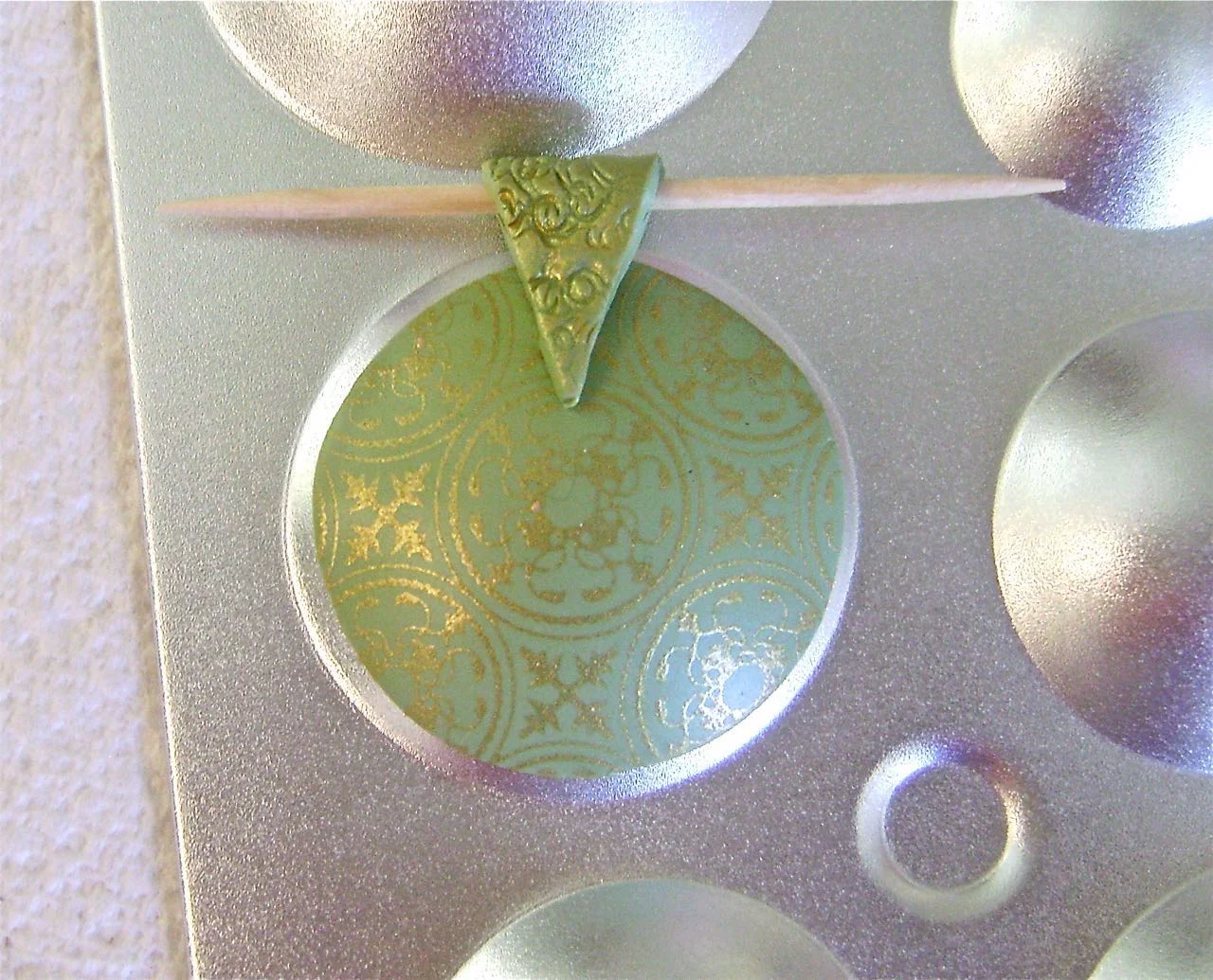 step 7 - Fold the clay over a toothpick. Remove the toothpick. Use a tissue blade or craft knife to cut the strip into a 'V' shape with the bottom center no smaller than .25" wide. Replace the toothpick and press the bail to the pendant.