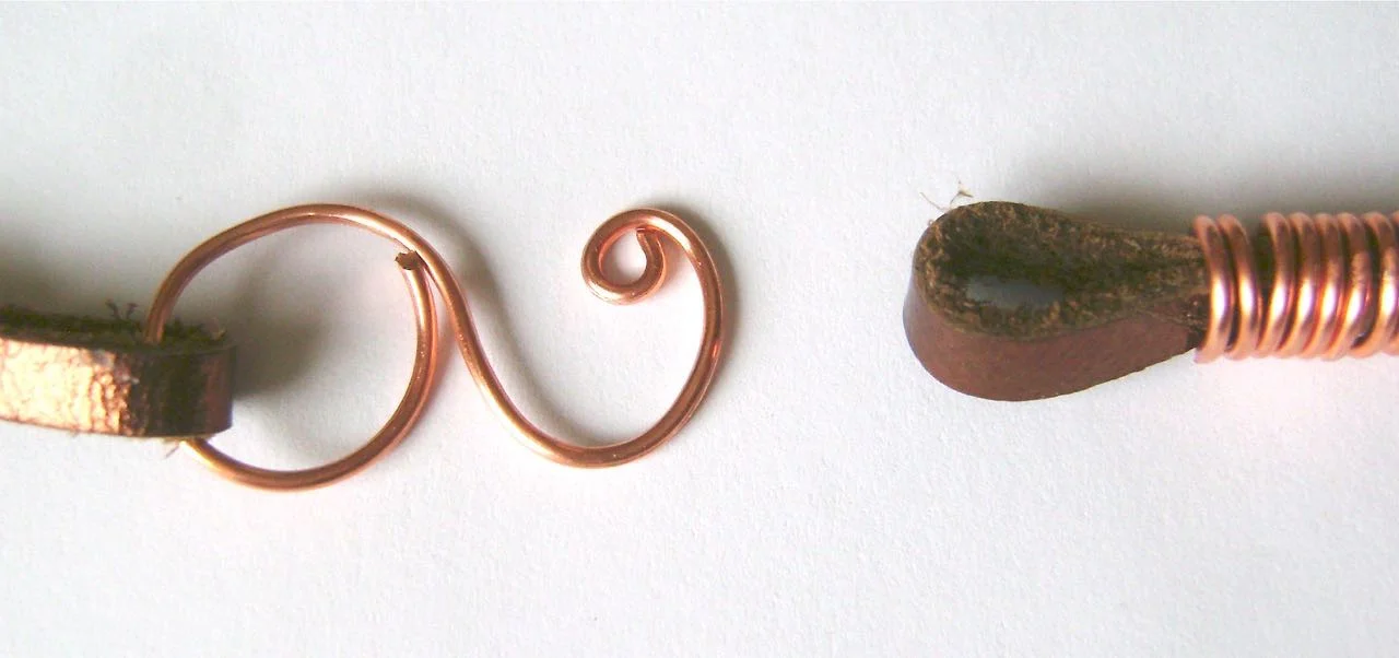 step 13 - Create an “S” shape with a piece of wire by smoothing one end around a magic marker or other round tool and the other piece of wire around a smaller tool. Close the curve in the larger end. Curl the end wire of the smaller end. with round nose pliers. To fasten the necklace, slip the curled end of the wire through the loop in the leather cord.