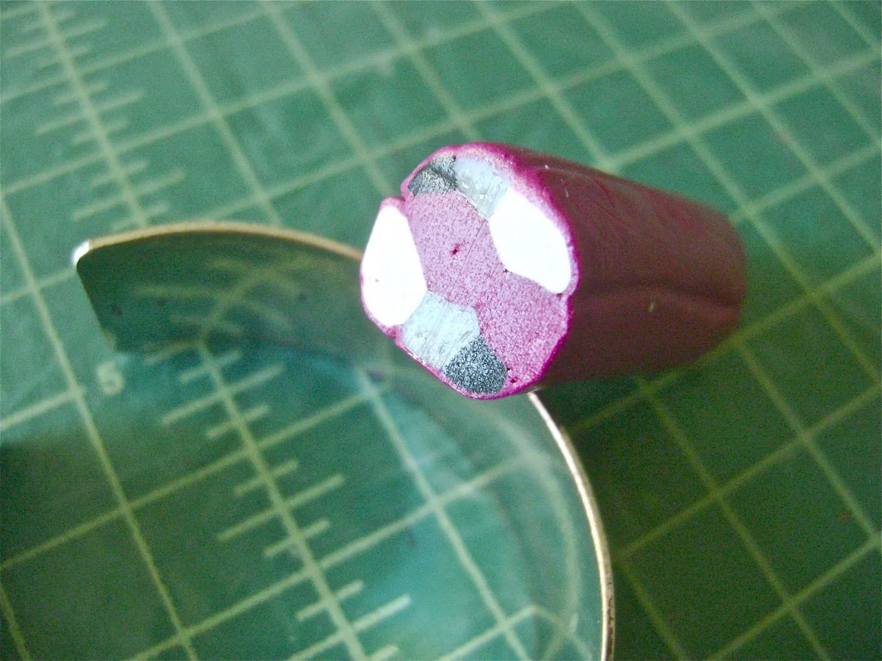step 3 - Once the tubes are grouped, put a piece of your dominant color through the conditioning machine and roll it out on the 7 or 8 setting. Wrap that thin piece around the grouped tubes. With your hand, gently roll the clay on the work surface to adhere the tubes to each other.