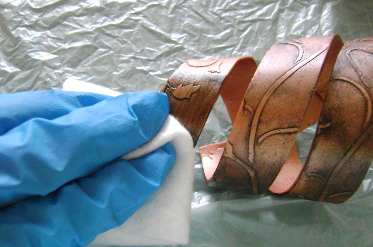step 7 - With a brush, working in small sections, apply a wash to the clay. Make the wash from a little water and acrylic black paint. Wipe away the paint immediately from raised areas with a soft cloth.