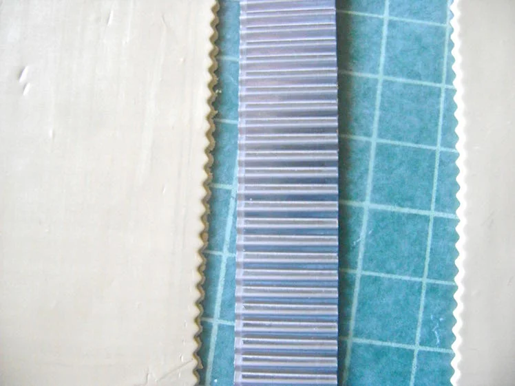 step 2 - Roll out the Ecru clay on the number two setting of the clay conditioning machine. You will need four pieces to join together to create the full mask. Cut the pieces into squares using a wave edge blade. See the note at the bottom of this page about why the wave edge blade is a better choice for piecing clay pieces together than a straight cut edge.