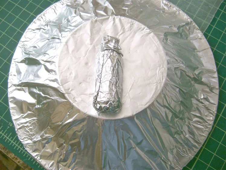 step 14 - Cover a large soup bowl with aluminum foil. Wrap a wine cork in foil leaving a stem on one end to create a shape that mimics a nose. Place it on the center of the bowl.