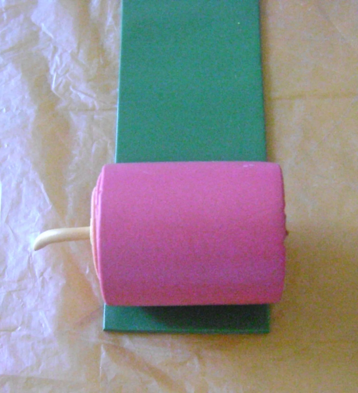 step 7 - Cut a piece of green clay rolled on machine setting #4, to measure the same width as the jellyroll. Cut the green edge straight and press it against the pink clay. Roll until the pink is encased in green.