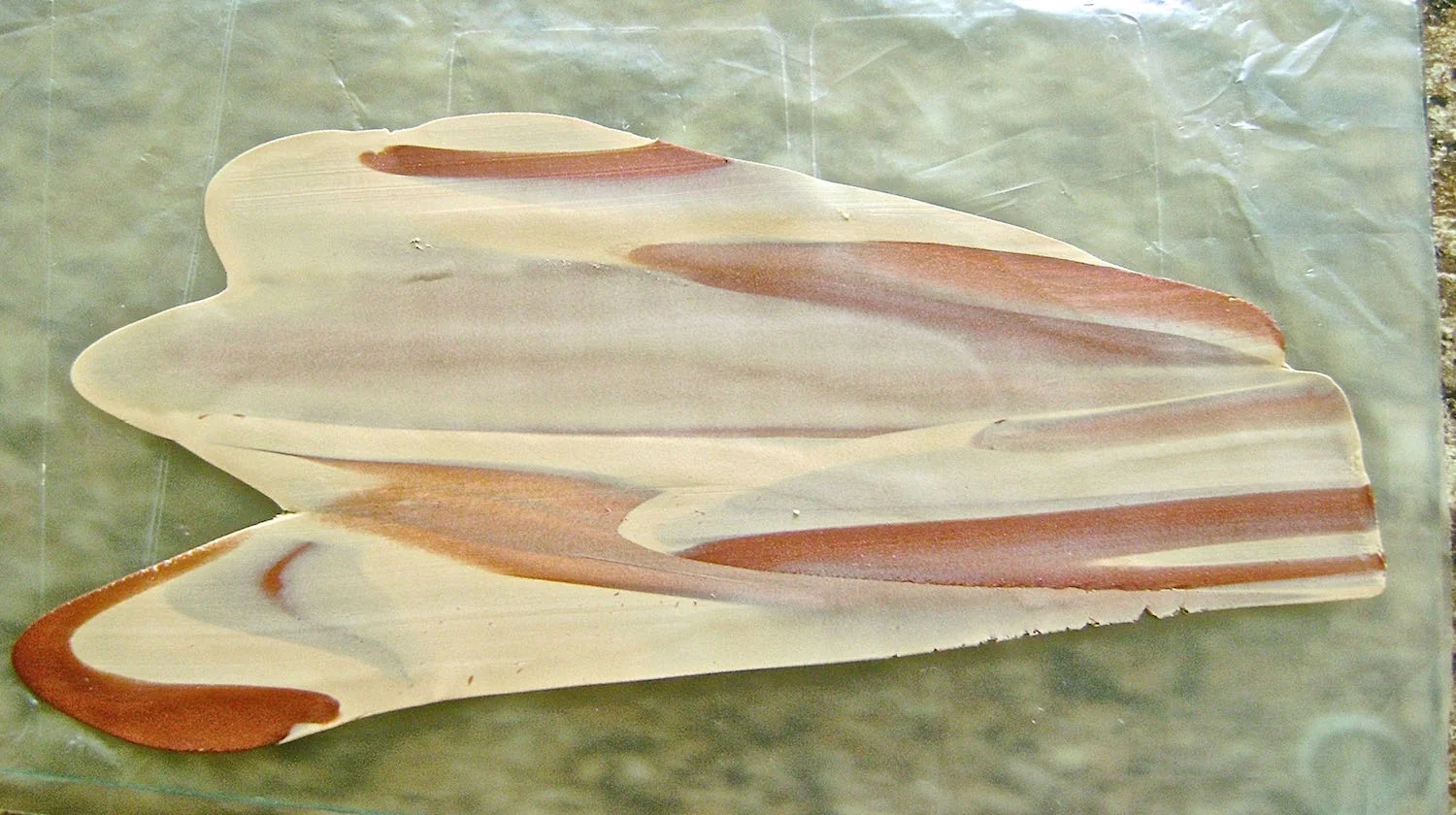step 5 - Make thin layers of mixed clay to cover the foundation. Begin by cutting down throughthe clay stacks to create 1/2” wide slices. Roll each in the palm of your hands. Twist the rolls three or four times. One by one, put them through the machine on the #1 setting. Roll the pieces again in your palms, twist three or four times then put them through the machine on#6 setting. 