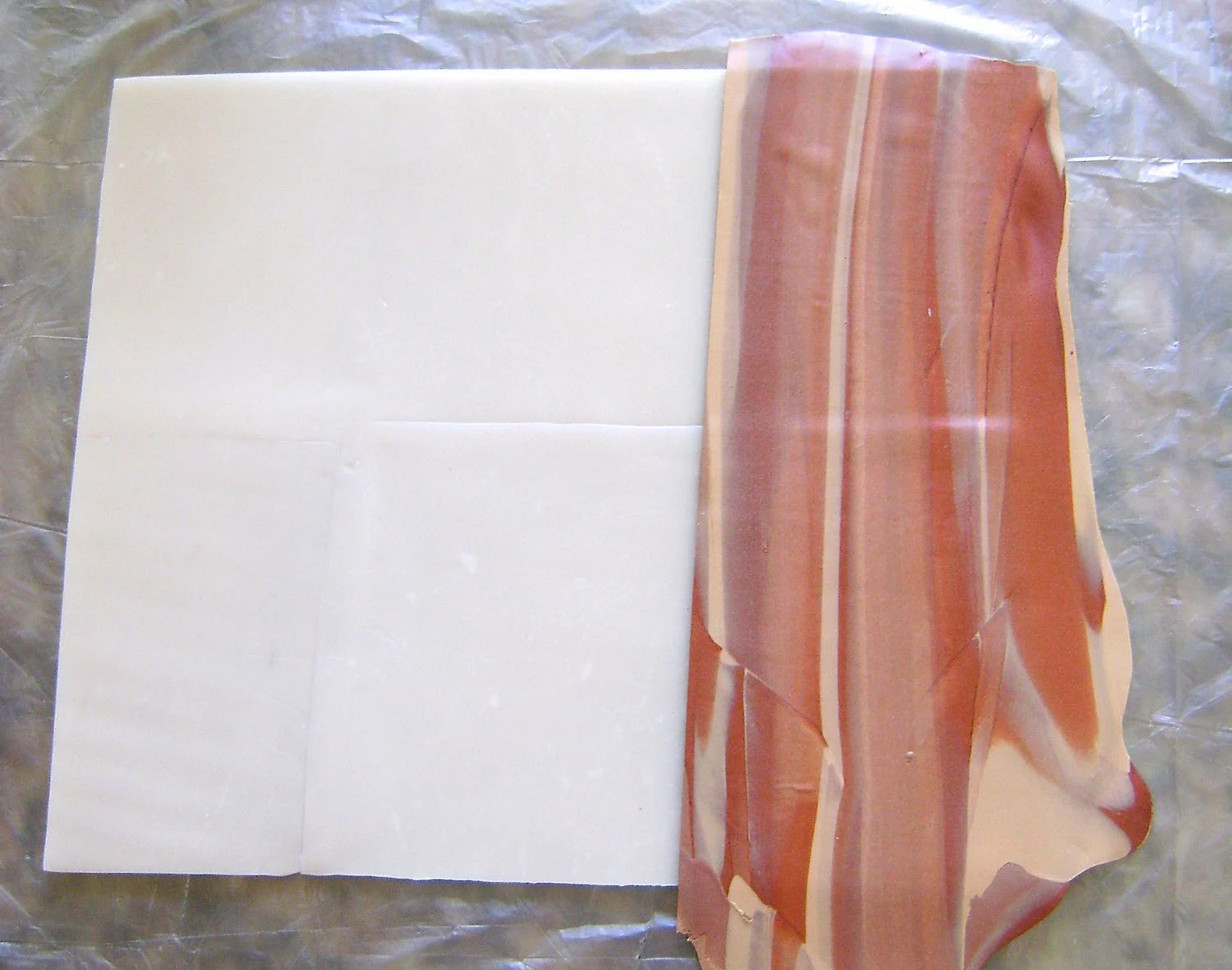 step 6 - Cut a straight side edge on one of the thin layers. Position it on the large translucent rectangle. Continue adding thin layers, trimming the sides as necessary, until the rectangle is covered. Blend the seams with your fingers. Place wax paper over the clay and flip it over. Cut away clay that extends beyond the rectangle. Turn the clay back to the right side.