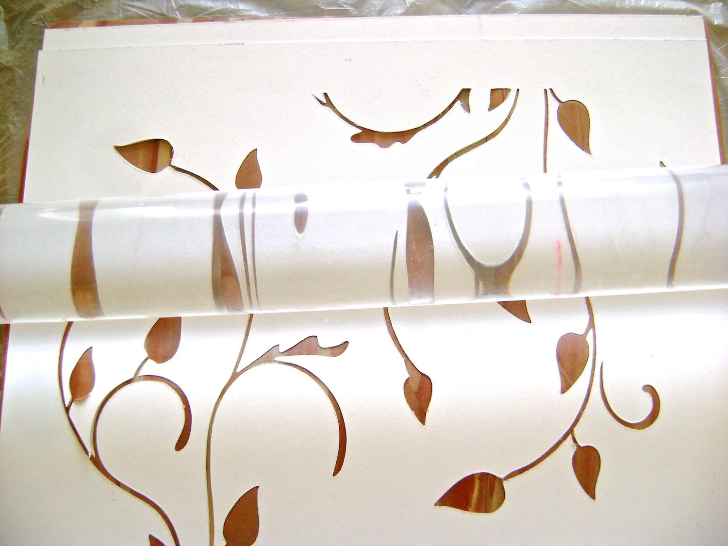 step 7 - Print the leaf stencil on card stock. Use a craft knife to cut out the images. Rub powder on the back of the stencil and place it on the clay. Run an acrylic roller across the surface to transfer the image to the clay. The clay should be flush with the surface of the card stock for dimensional results. Carefully peel away the stencil.