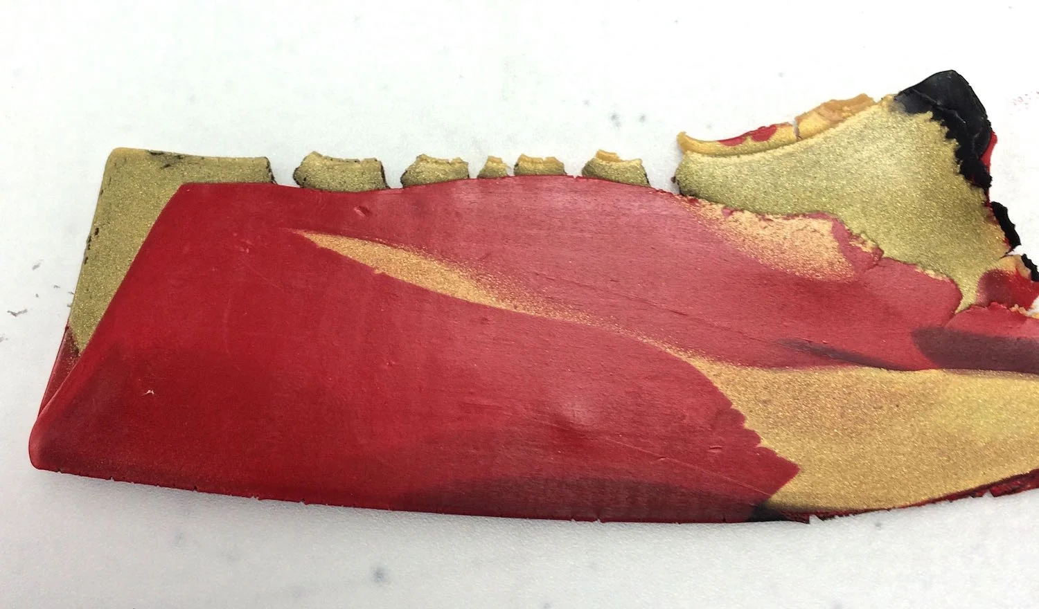 step 4 - Pass the pieces vertically into the machine on # 3 setting. Fold the piece in half with the foil on the outside and roll again. Fold the piece horizontally and roll again. Keep passing the clay through the machine until you like the color mix.