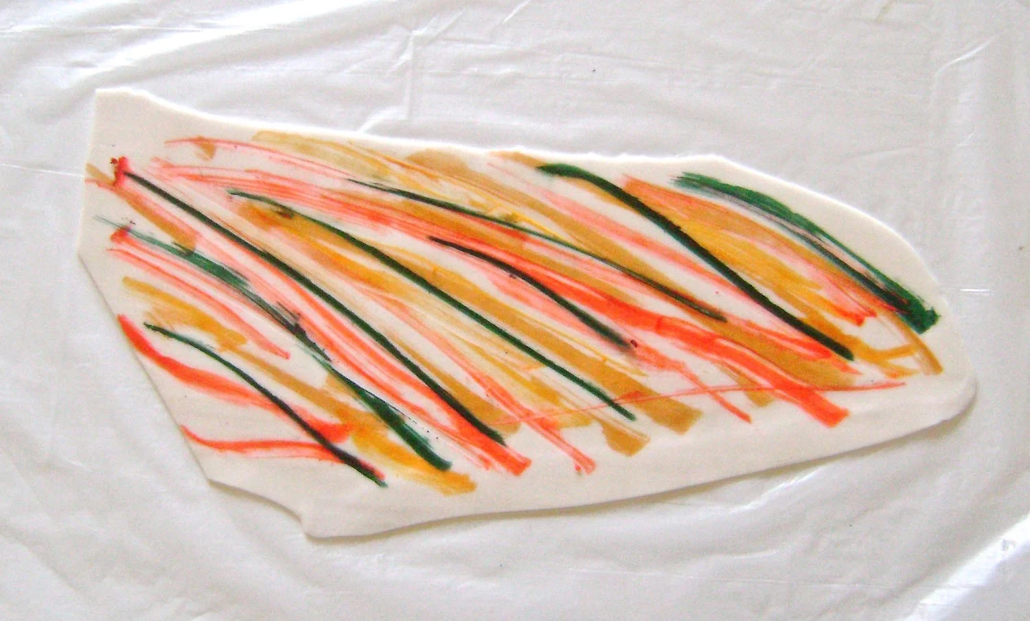 step 2 - Plastic gloves will make clean up easier from this point forward. Move alcohol pens across the clay in random patterns. Choose which colors you want to dominate the pendant. Make more marks with them. It's not necessary to fill every blank space of your clay. The colors will blend together later. The less color you apply the lighter the finished piece will be. Conversely, the more color you apply, the darker the piece will appear overall. 