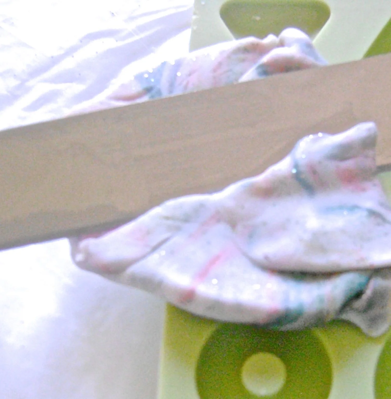 step 7 - Press the clay into the large teardrop mold. Use a tissue knife to slice away the excess. Use the blade in an almost parallel angle to the mold, moving it back and forth through the excess clay, creating a flat top. 