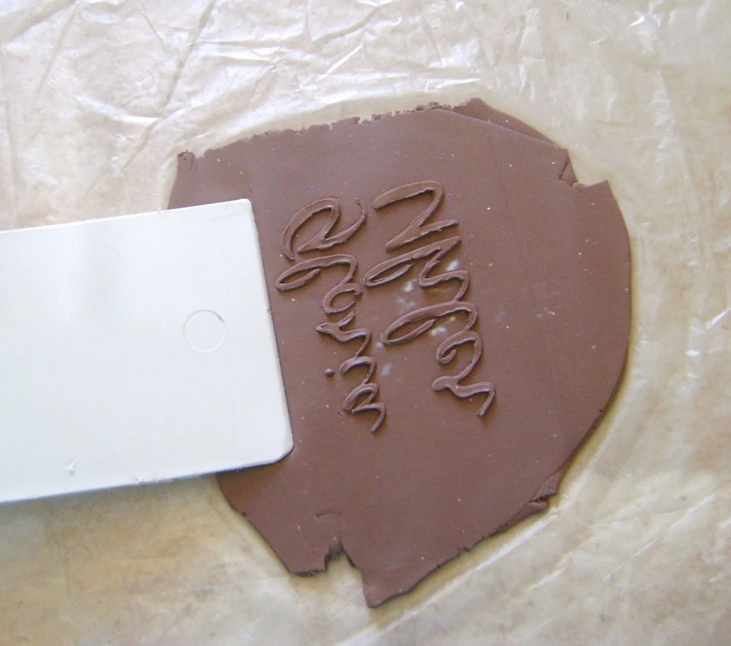 step 5 - Press a plastic spatula outside the signature area to flatten the surrounding clay slightly.