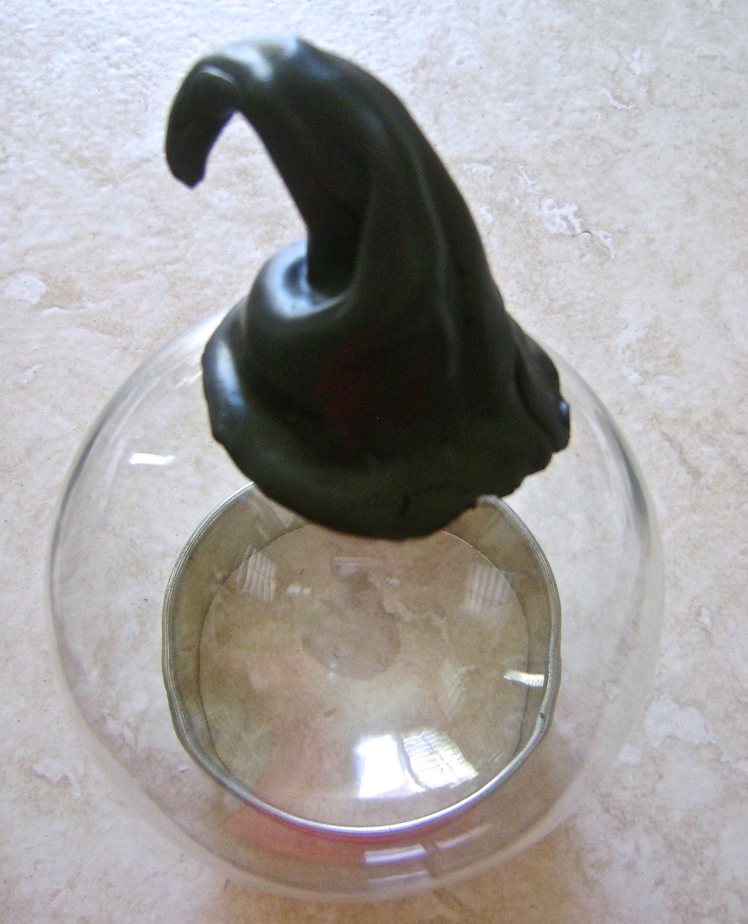 step 4 - Pass the rest of the clay through the conditioning machine on #2 setting. Shape clay around the foil blending the vertical edges and pinching it into shape. Pull out the foil and discard it. Set the hat on the ornament opening. Put the ornament on a cookie cutter or a clump of scrap clay to balance it. Continue shaping and bending to create folds in the hat. 