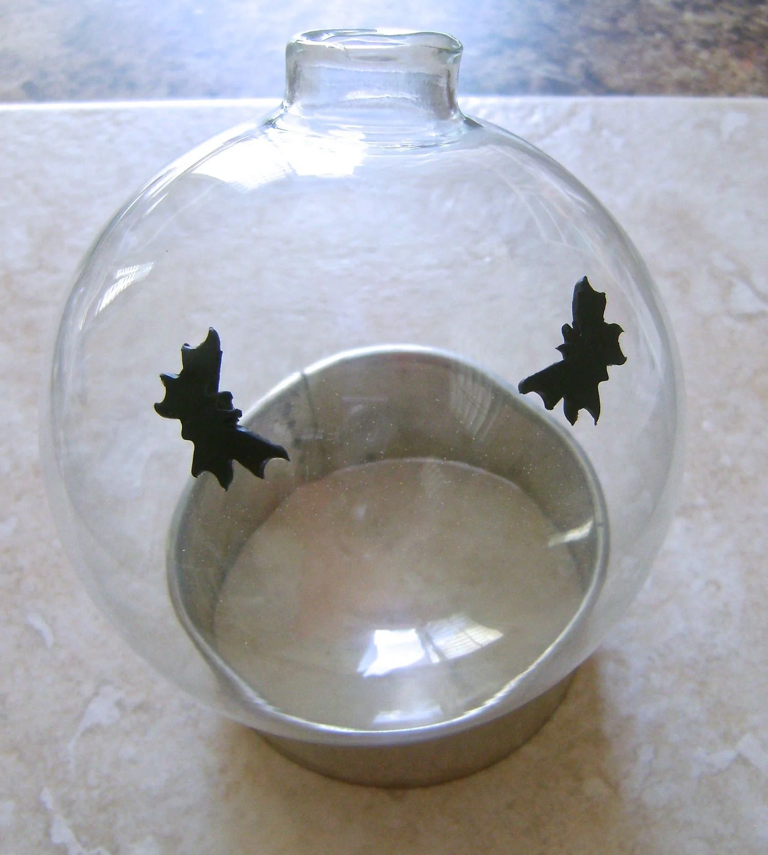 Step 9 - Plan your witch placement (see step 11) on the ornament and press bats on the glass to surround them. Set the ornament on a large round cookie cutter for support while baking.