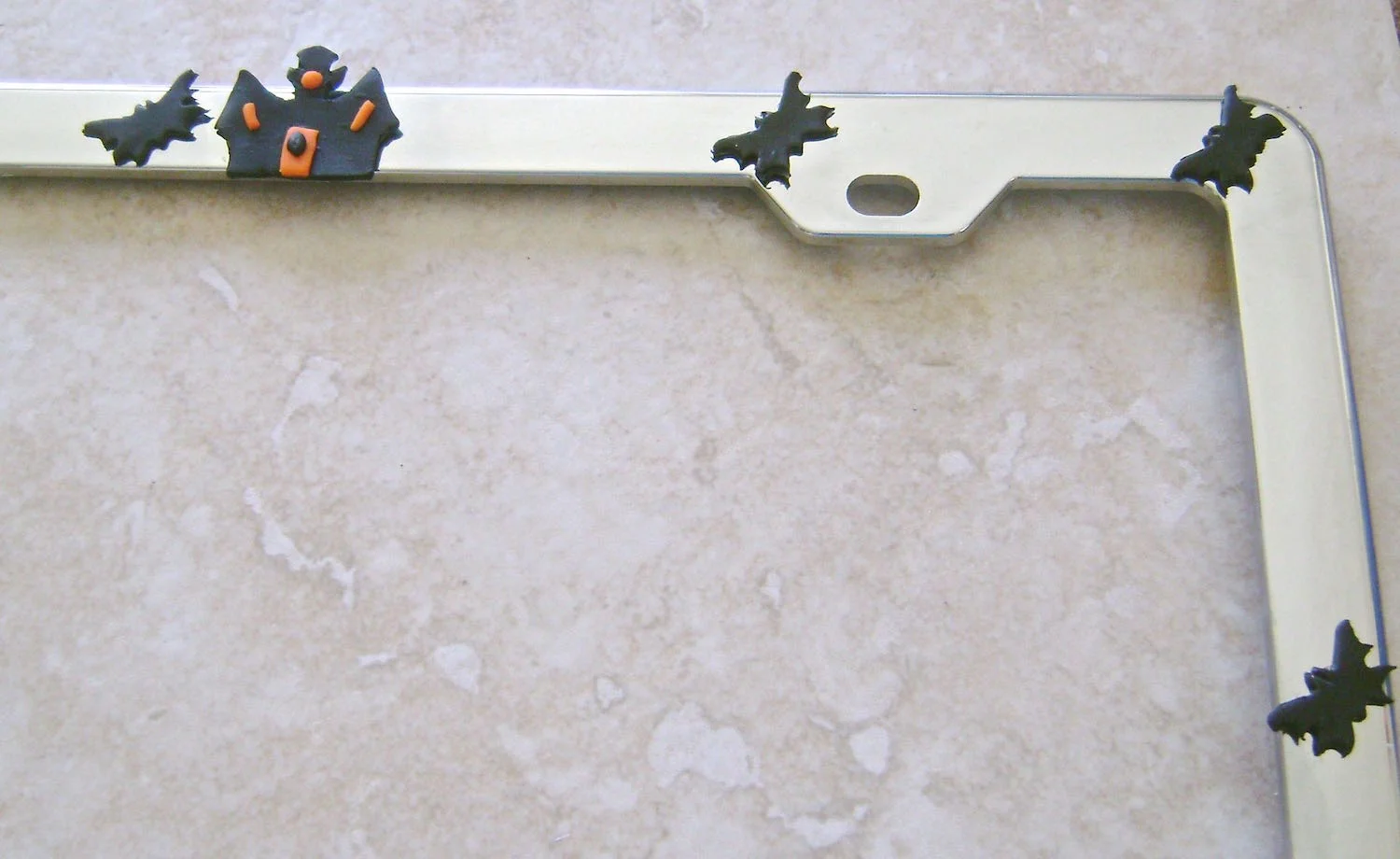 step 11 - Apply E6000 adhesive to the wrong side of the haunted house and bats. Attach them to the frame as desired.