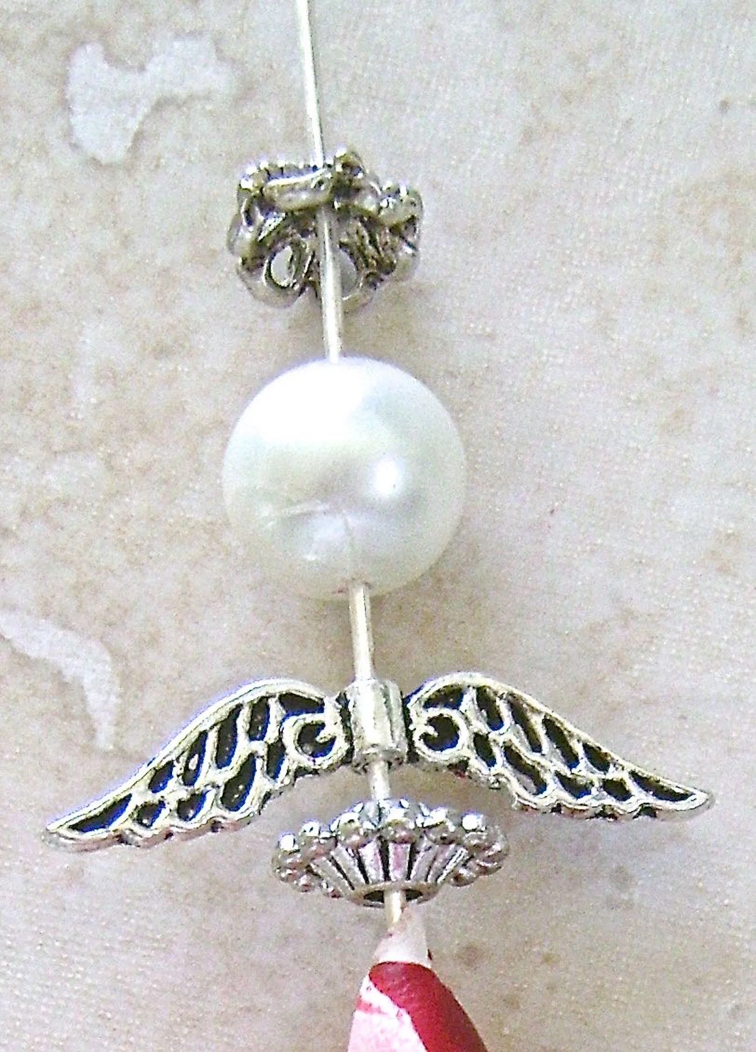 step 8 - Slide a decorative bead onto the wire followed by angel wings, the pearl, and a decorative silver bead cap. Press them against the clay.