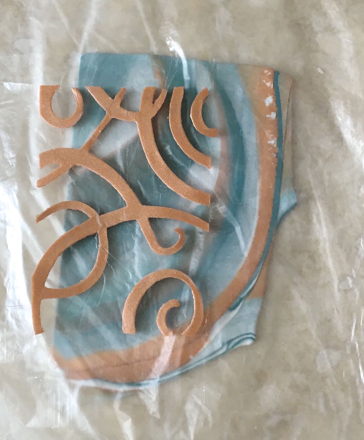 step 9 - Hold the design over the blended clay. The clay will stick to the film allowing you to move it around and decide on placement. When you’re happy with it set it down on the blended clay.