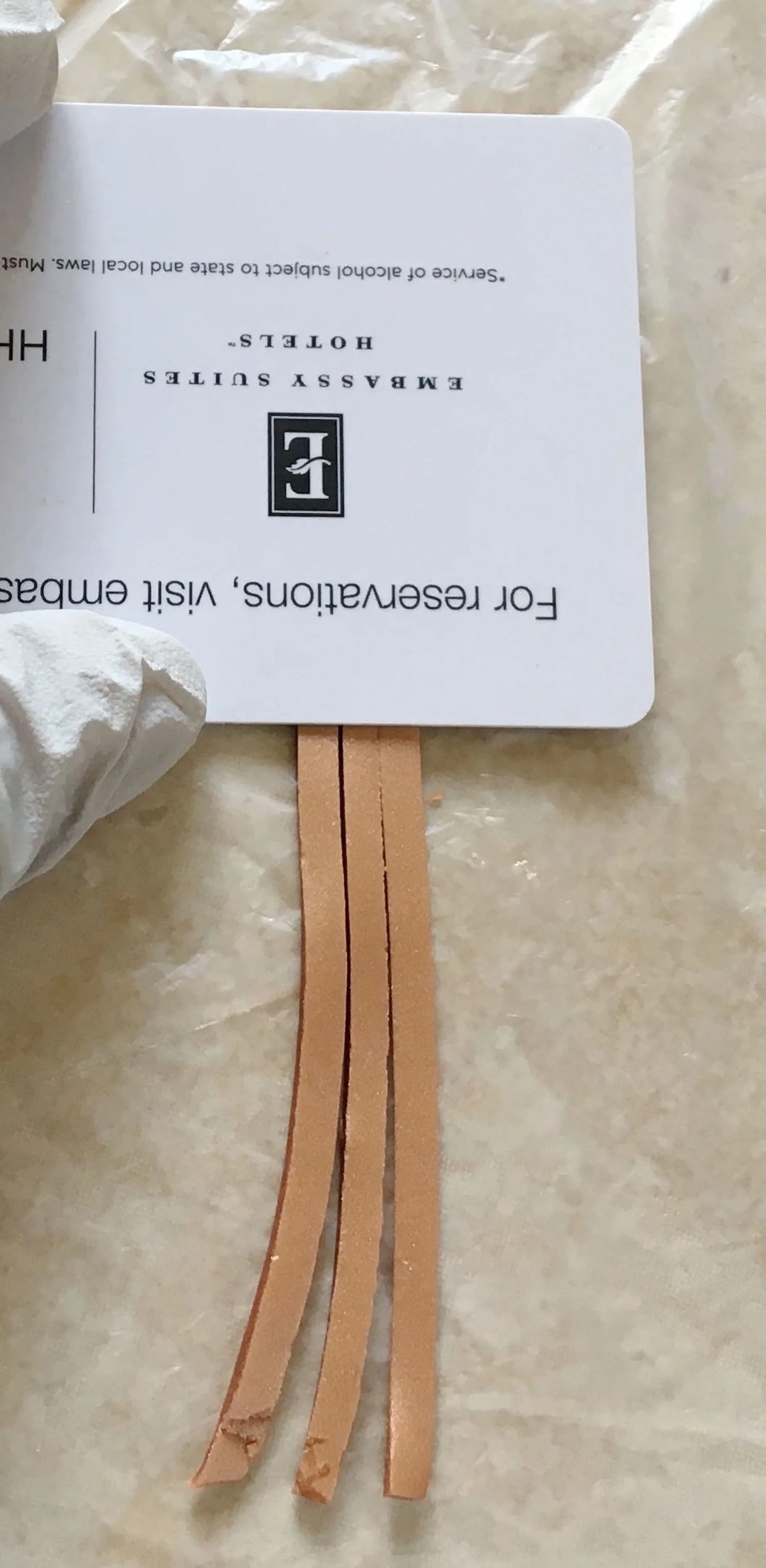 step 12 - Create the bail. Slice three solid copper clay pieces to match the widths of the scroll pieces and about 1.50” long. Press an old credit card to the top of them.
