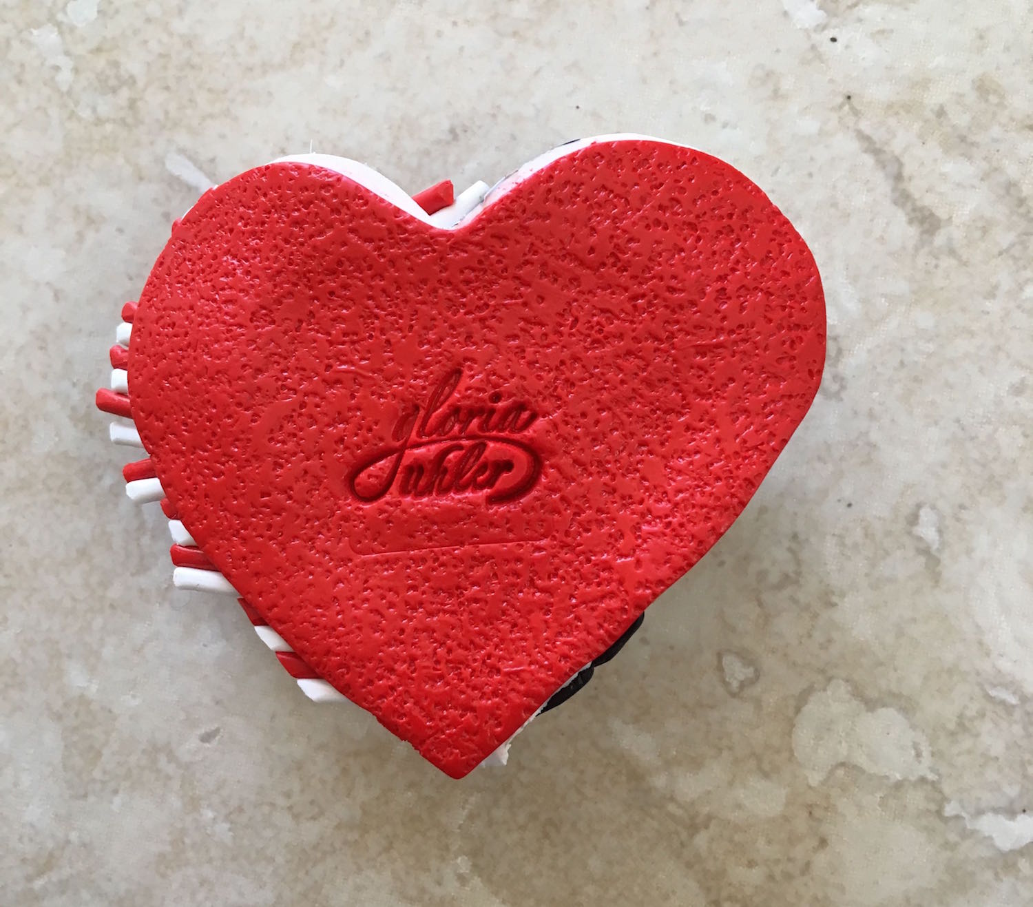 step 10 - Add texture to a piece of red clay with rough sand paper. Cut it out with the large heart cutter and press the red clay over the white clay. The texture will prevent the pendant from sticking to your skin when you wear it.