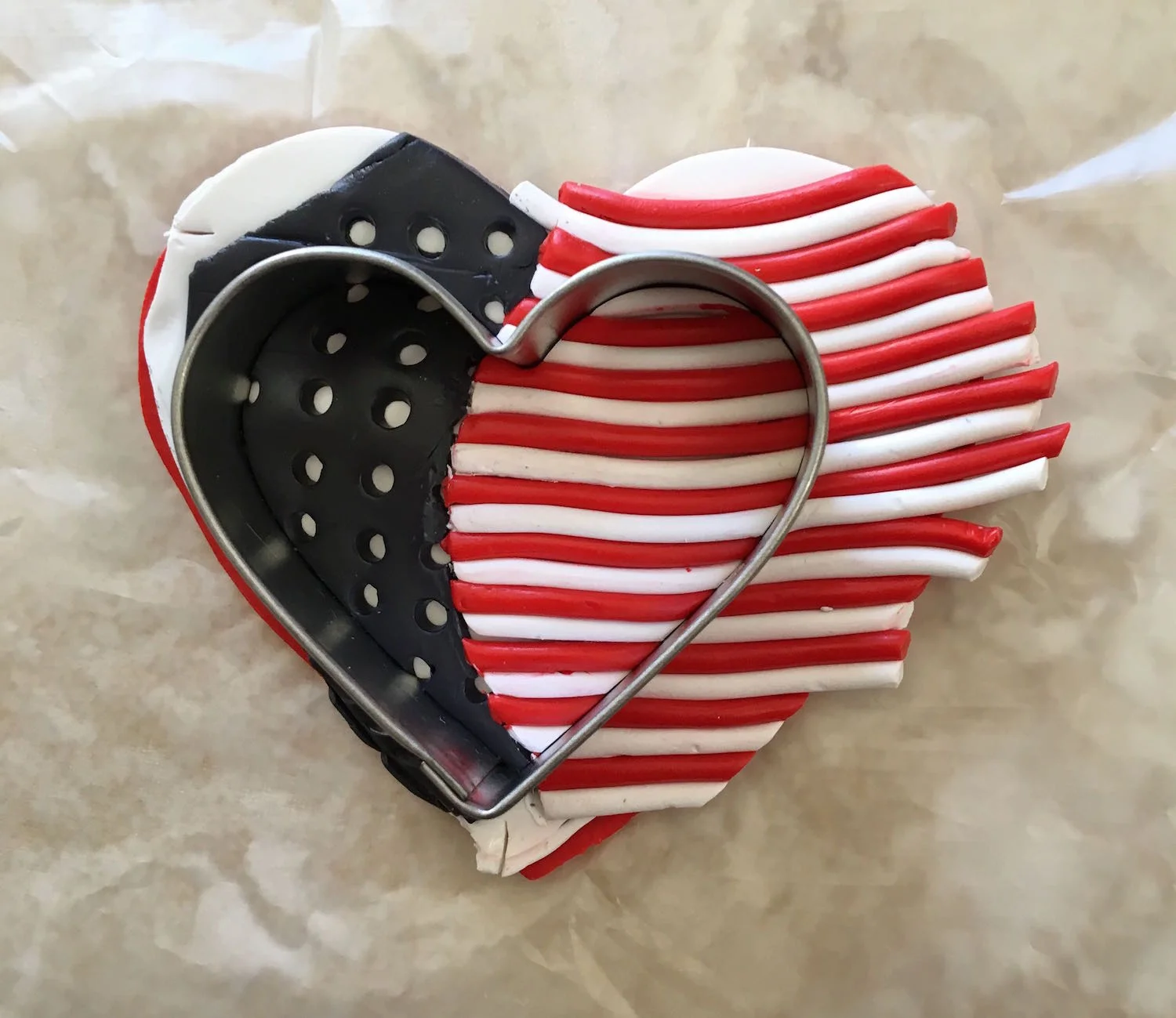 step 11 - Cover the clay with deli film and flip all layers over. Press down on the cutter. The top and bottom layers will seal together trapping air inside the clay, giving the heart a puffy shape.
