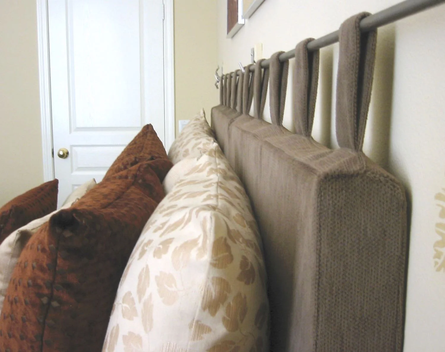 The tabs and bolster hang straight down from the rod and the bolster rests flush against the wall.