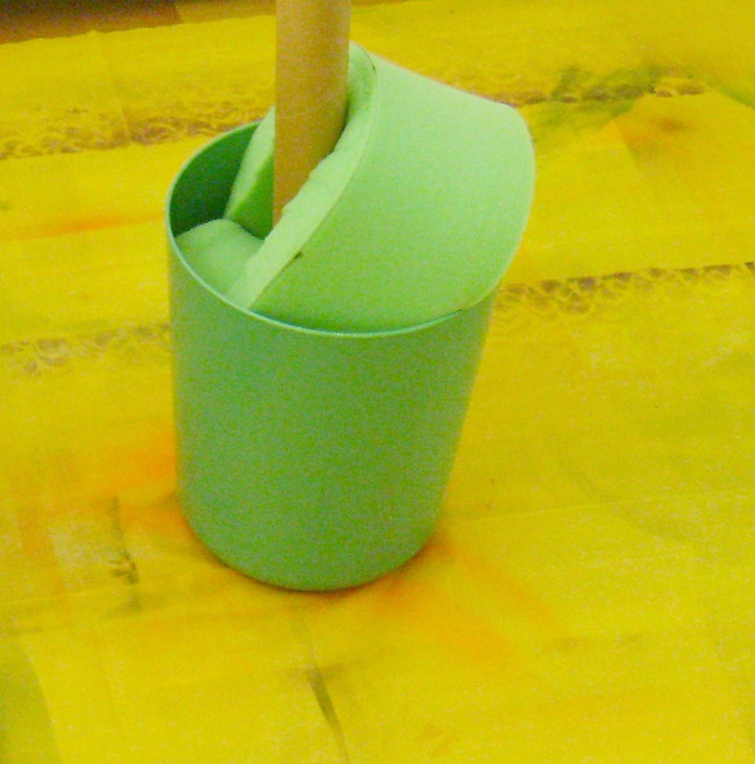 step 1 - Cover the floor with a plastic tarp to protect it. In the center of the tarp place a small wastebasket to create a stand. Place a tube in the center of it. I used a 5’ cardboard tube and stuffed the basket with odd pieces of foam to hold the tube upright.