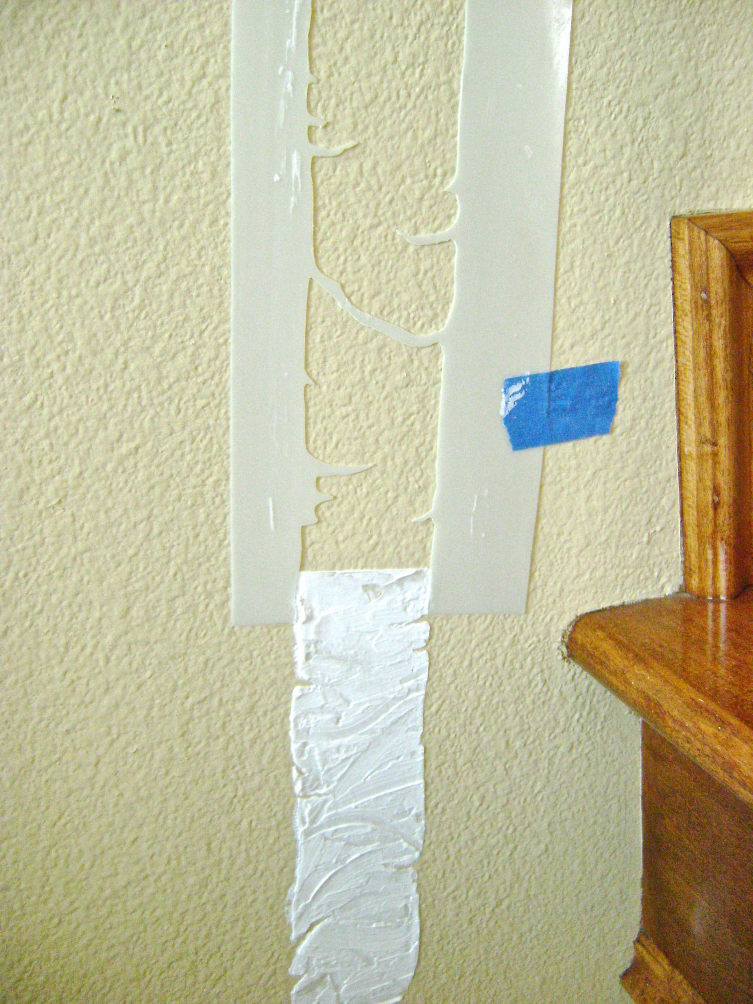 step 6 - Because you would have to wait for one trunk section to dry before repositioning the stencil again, you may want to cut off the blank margin on one edge of the stencil leaving it open at the bottom. This will allow you to align the stencil edges with the finished edges of the previous trunk and continue working. Use the knife to blend the joined ends of added trunks sections. Keep an oversized towel and a sink filled with sudsy warm water to wash caulking off both sides of the stencil before using it again.