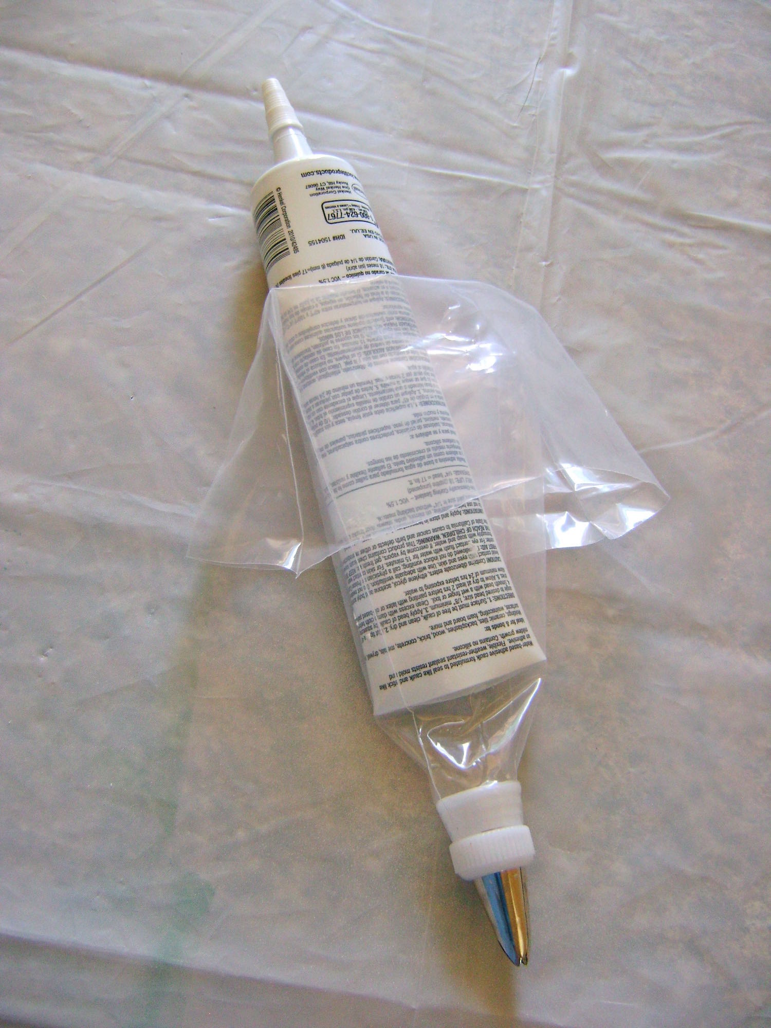 step 12 - Fold the top half of the bag over into a cuff. Put the cap back on the tip of the caulking tube then cut open the opposite end and slip it into the cuffed bag.