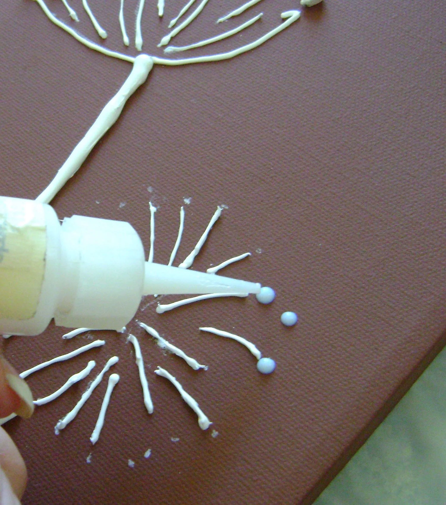 step 15 - Place small dots of glue on the marks you created for the blooms. These give you a general outline of the flower. More kernels are needed to complete the image. Add them working from the outline toward the center until you have the number of kernels that appeal to you.