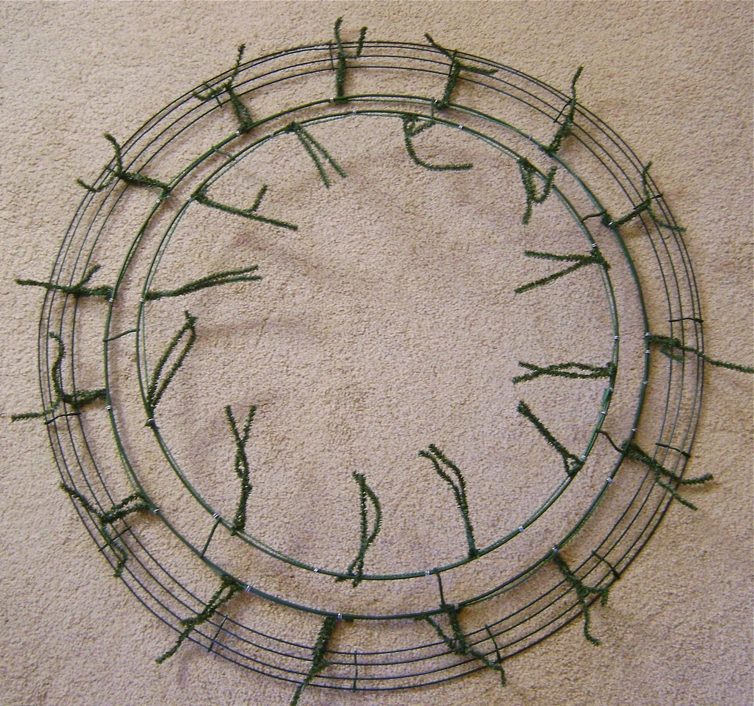 step 1 - On a work surface, place the small wreath inside the larger wreath with even spacing between the two. Push the twist ties on the inner circle toward the center.