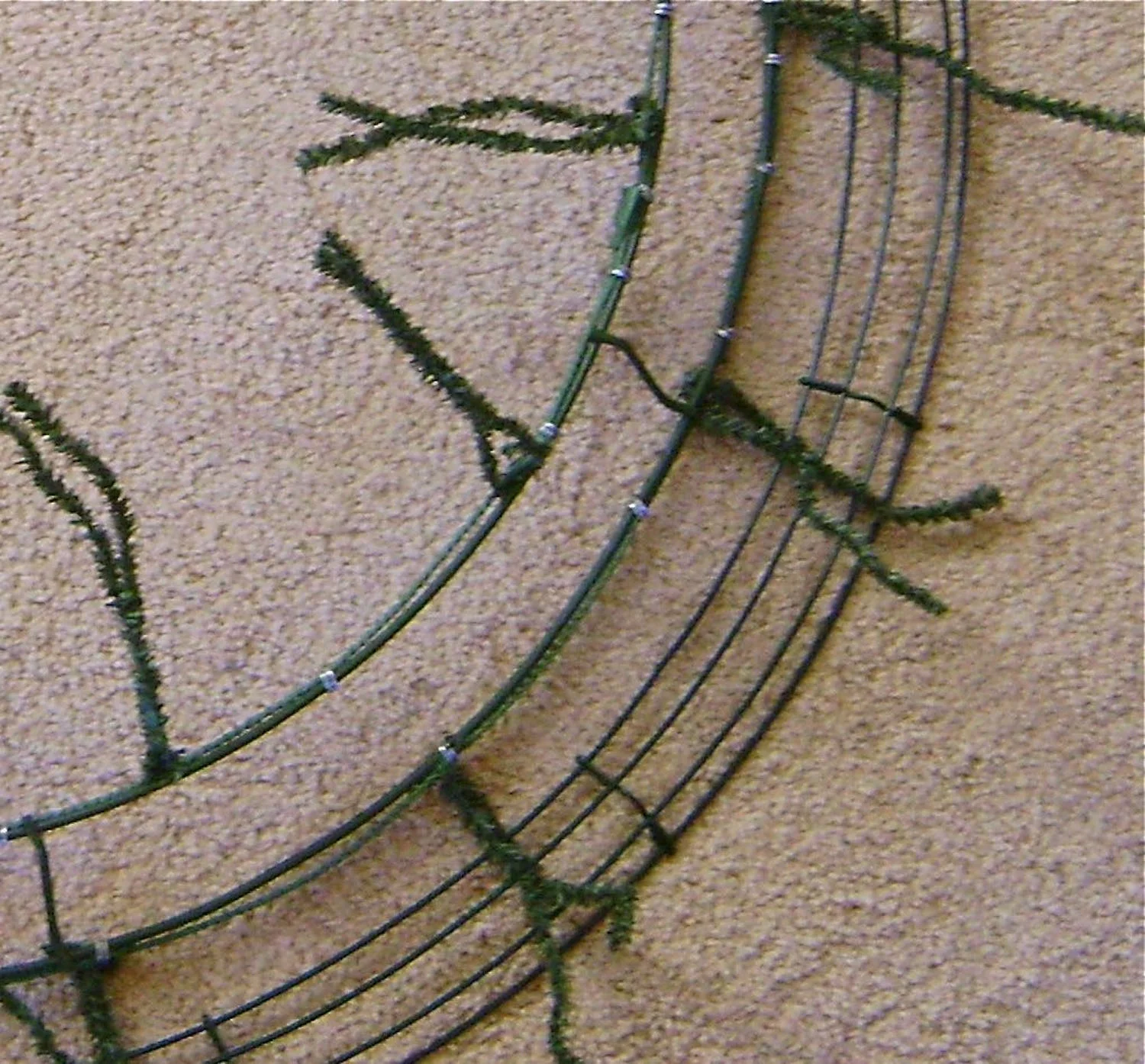 step 4 - Add 4 rows of garland working in a circle. Begin at the outside of the wreath ( # 1) attaching garland to the outer most wire of the larger wreath. Use the excess ends of the twist ties to connect the garland.
