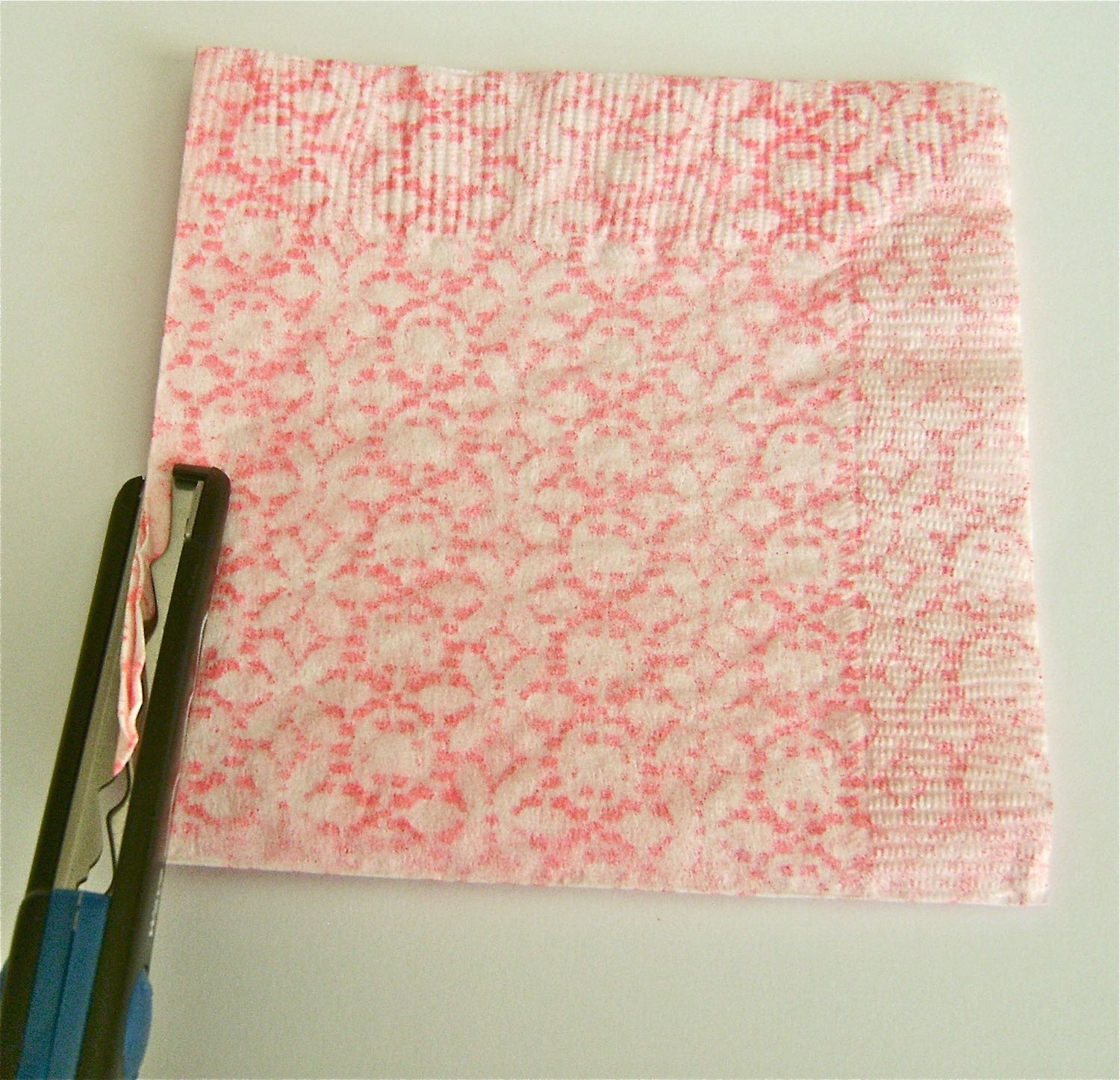 step 2 - Return the napkin into the original folds creating a 5”x5” square. The folds should be on the left and at the bottom. Trim left and right outer edges with decorative edged scissors.