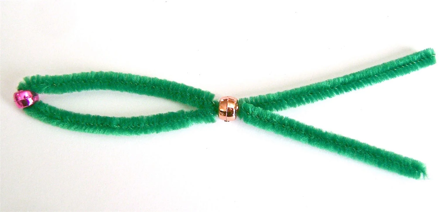 step 4 - Slide a bead into the center of a pipe cleaner. Slip both ends of the pipe cleaner into a second bead.