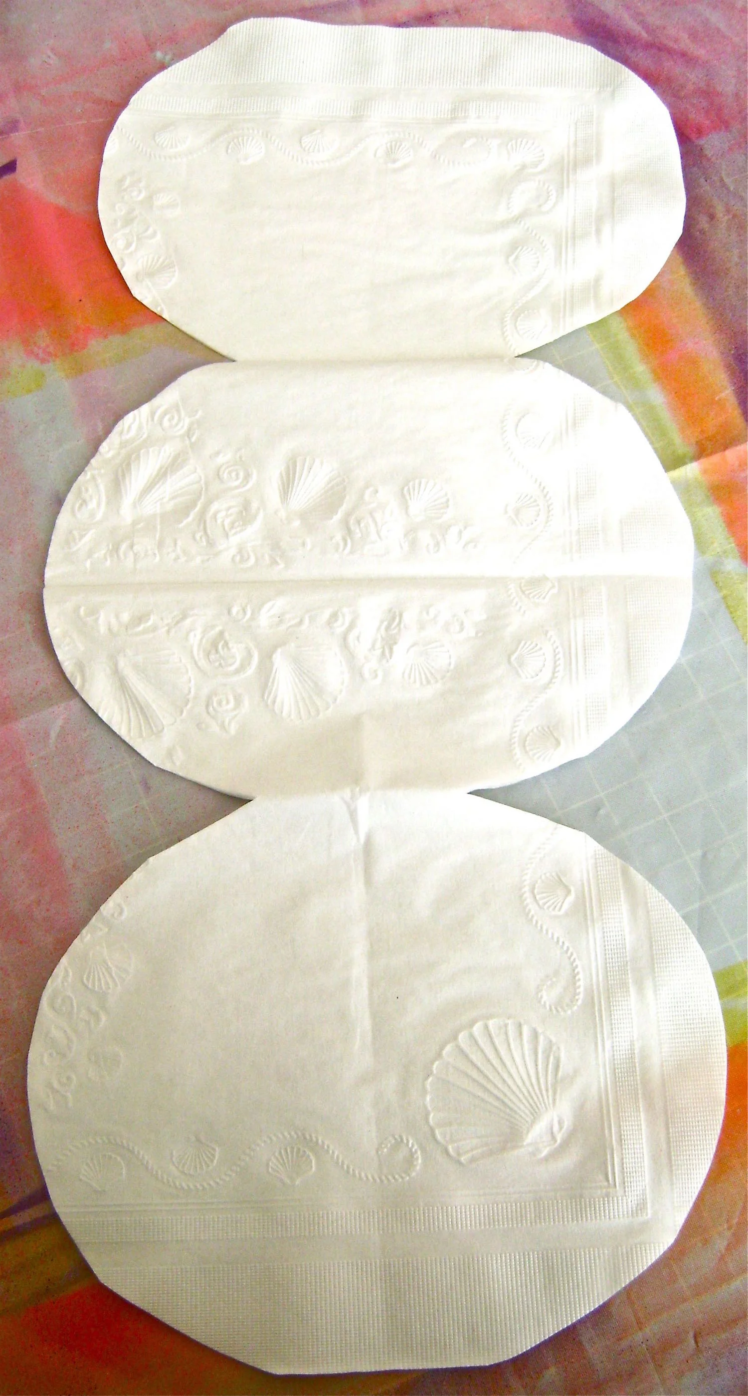 step 9 - Open the napkin flat and separate the two layers. Fold one layer as in step #2 and trim the round shape so that it’s smaller in width than the other layer.