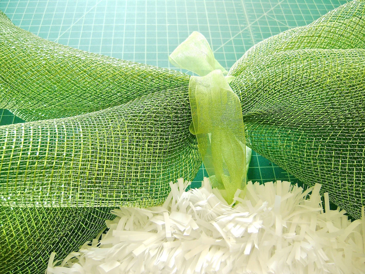 step 10 - Cut two pieces of deco mesh to 30” long. Fold them diagonally and roll them up. Tie them together at the center with ribbon. Attach them to the ribbon on the egg. 