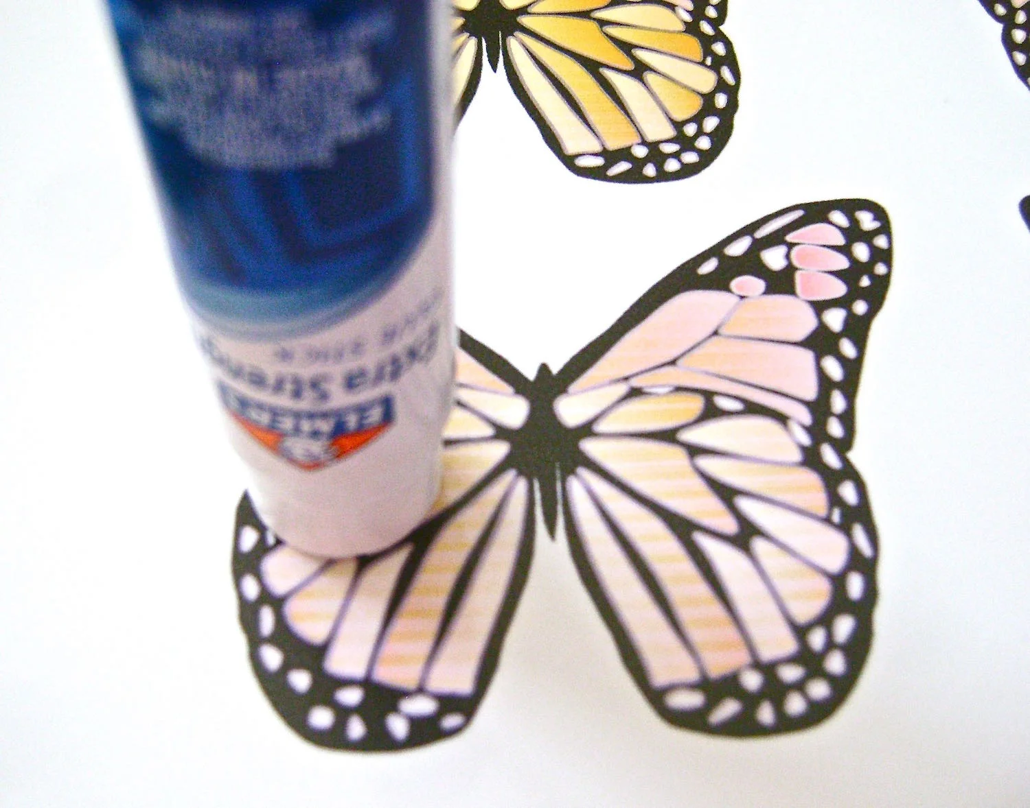 step 3 - Apply glue to the butterflies working on one at a time. Hold the glue stick flat against the printed image with light pressure. Work ina circular motion. Pressing down too hard on the glue stick will leave streaks of glue and lumps in what should be smooth wings.