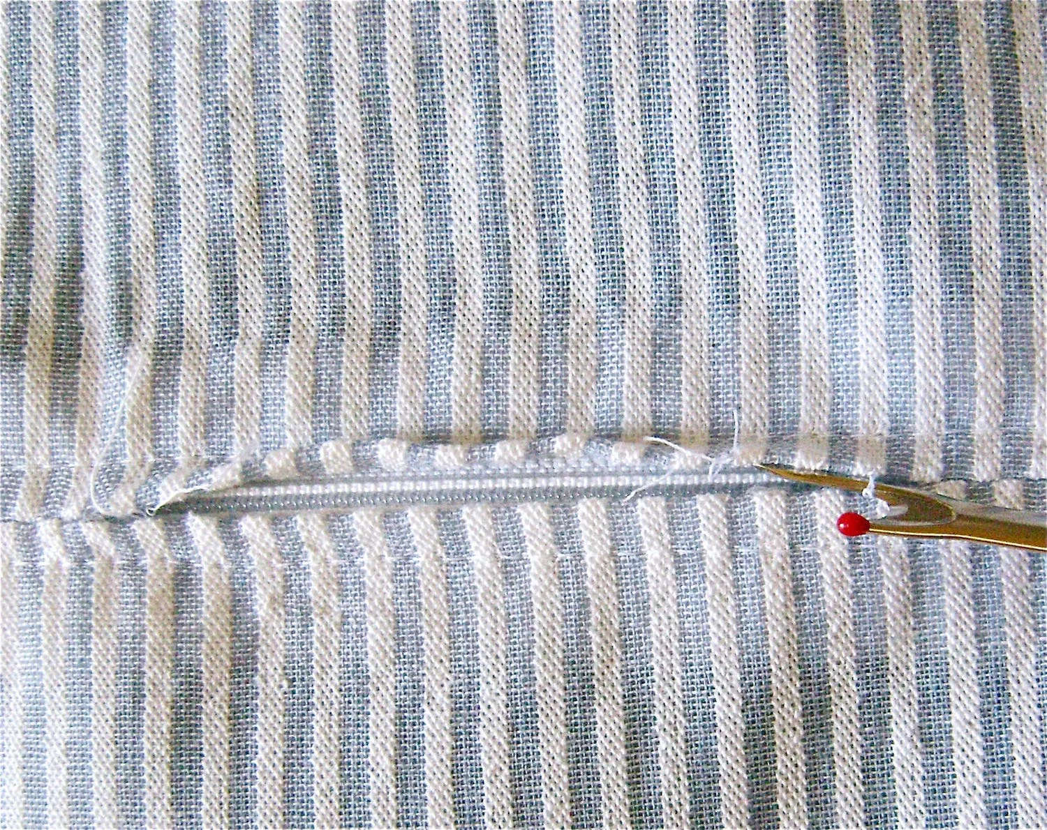 step 3 - On the right side of the fabric remove the basting stitch revealing the zipper. Open the zipper.