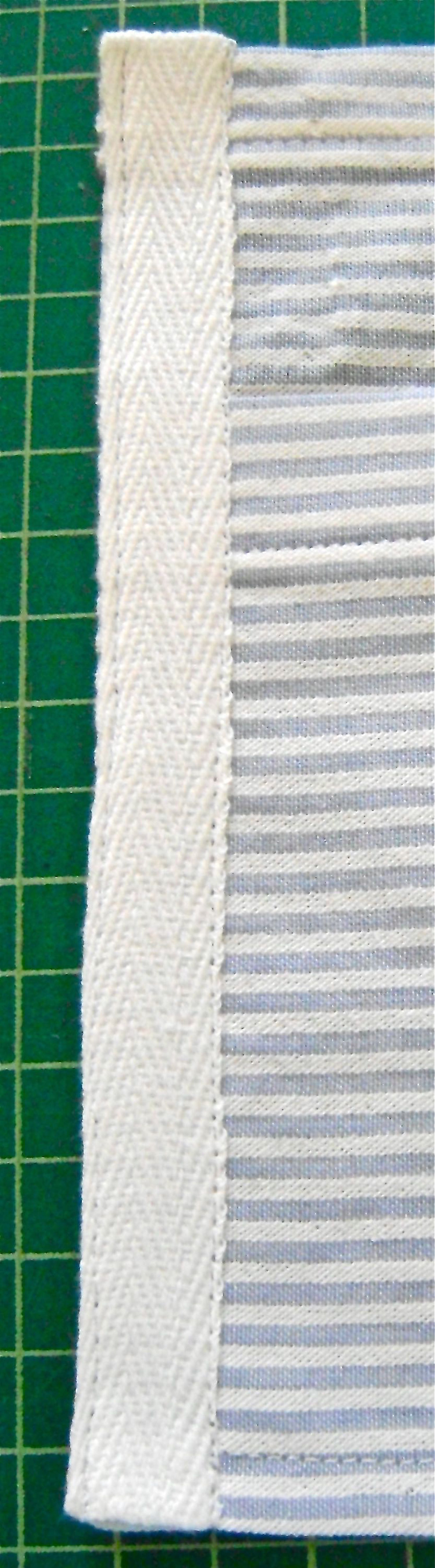 step 13 - Cut a piece of cotton tape to fit the left side of the pocket back. Turn the ends under and stitch close to the long edges of the tape. Repeat on the right side of the pocket back.