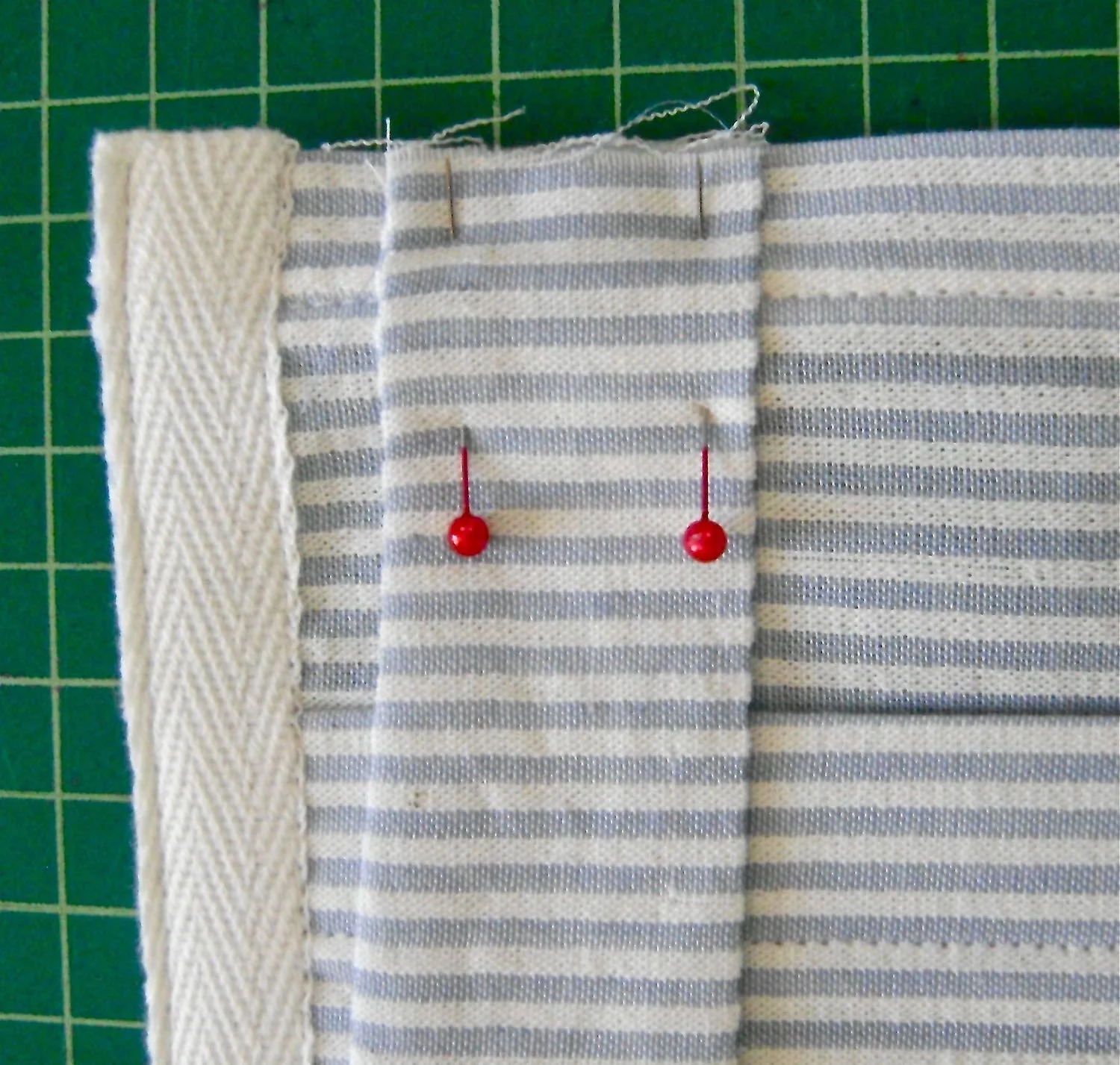 step 14 - Position straps on the upper front and back of the pocket back, one directly behind the other, one inch away from the tape. Stitch the straps 5/8” from the raw edges.
