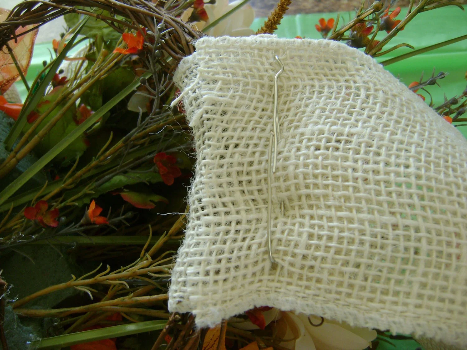 step 11 - If you prefer to hang your basket from a ribbon, double the length you need and cut a piece from the burlap. Fold the ribbon in half with the basket handle in between. Weave heavy wire in and out of the overlapped ends of the burlap to secure them together.