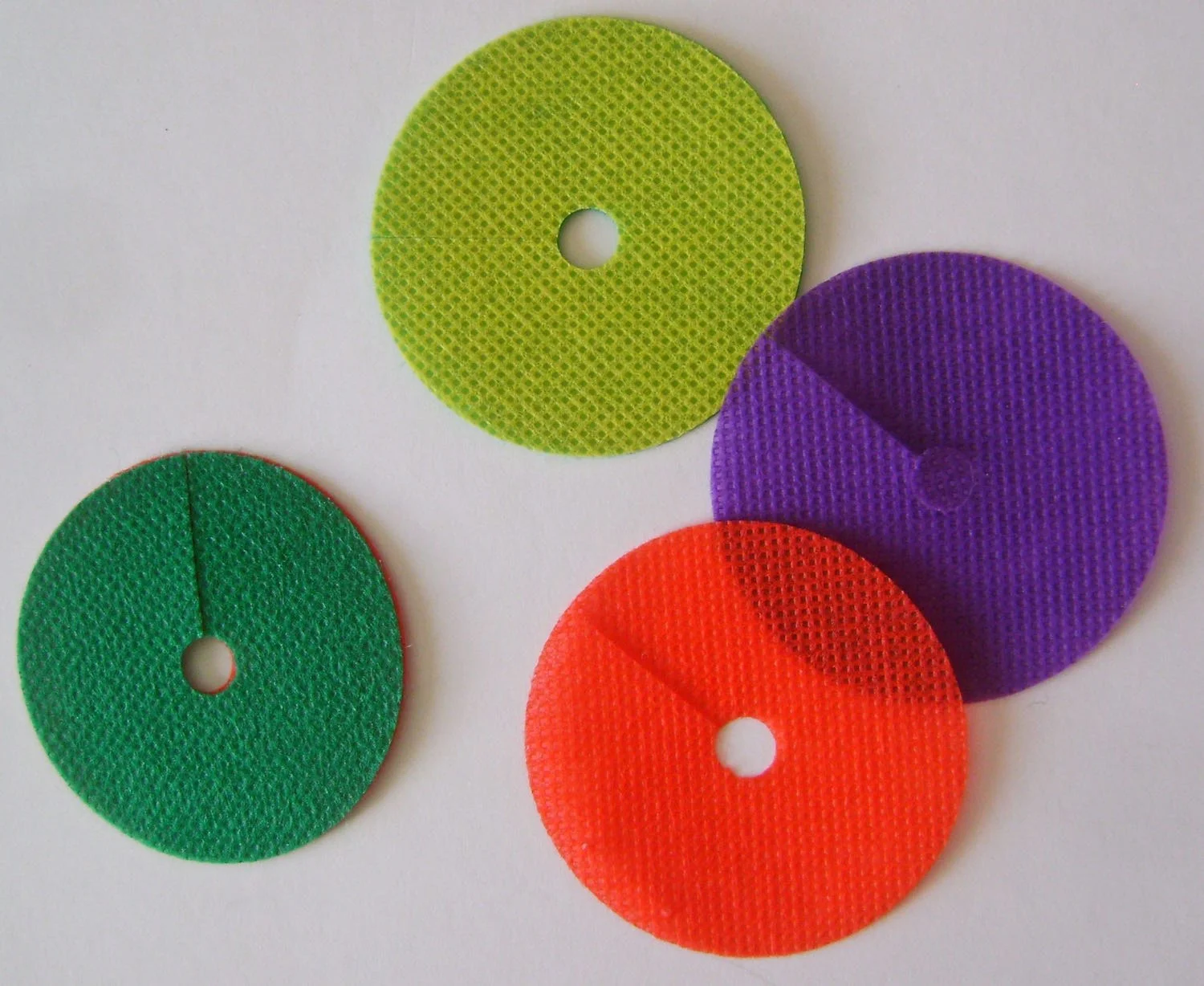 step 10 - Cut 14 discs measuring 2” round in a variety of colors. Cut a hole in the center of each and a slit from the outside edge to the hole. Use the glue stick to attach together two different colors until you have seven discs. 