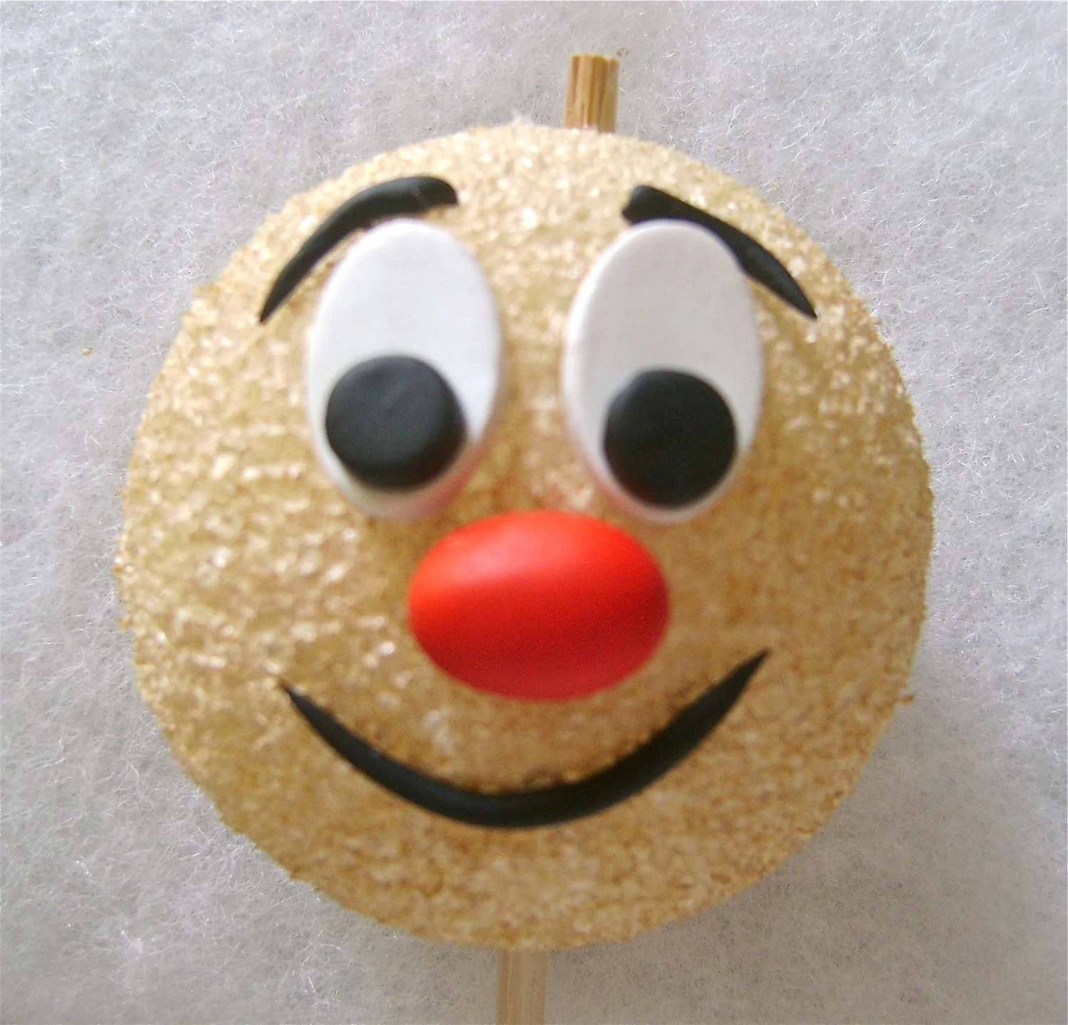 step 14 - Shorten the tooth pick to about .50”. Place hot glue on the end and stick it in the middle of the painted ball. Hot glue the other clay pieces to the face.
