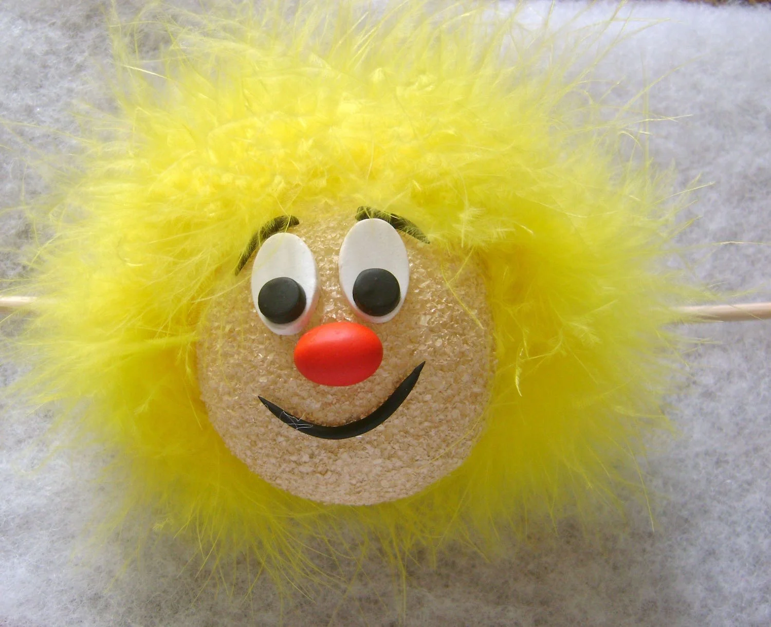 step 15 - Apply hot glue to the sides and center top of the face and press craft boa fur to the ball using a craft stick. Attach the ball to the wire coil of the photo cube by making a gash in the bottom of the ball, applying hot glue to the coil and and pushing the foam onto the coil.