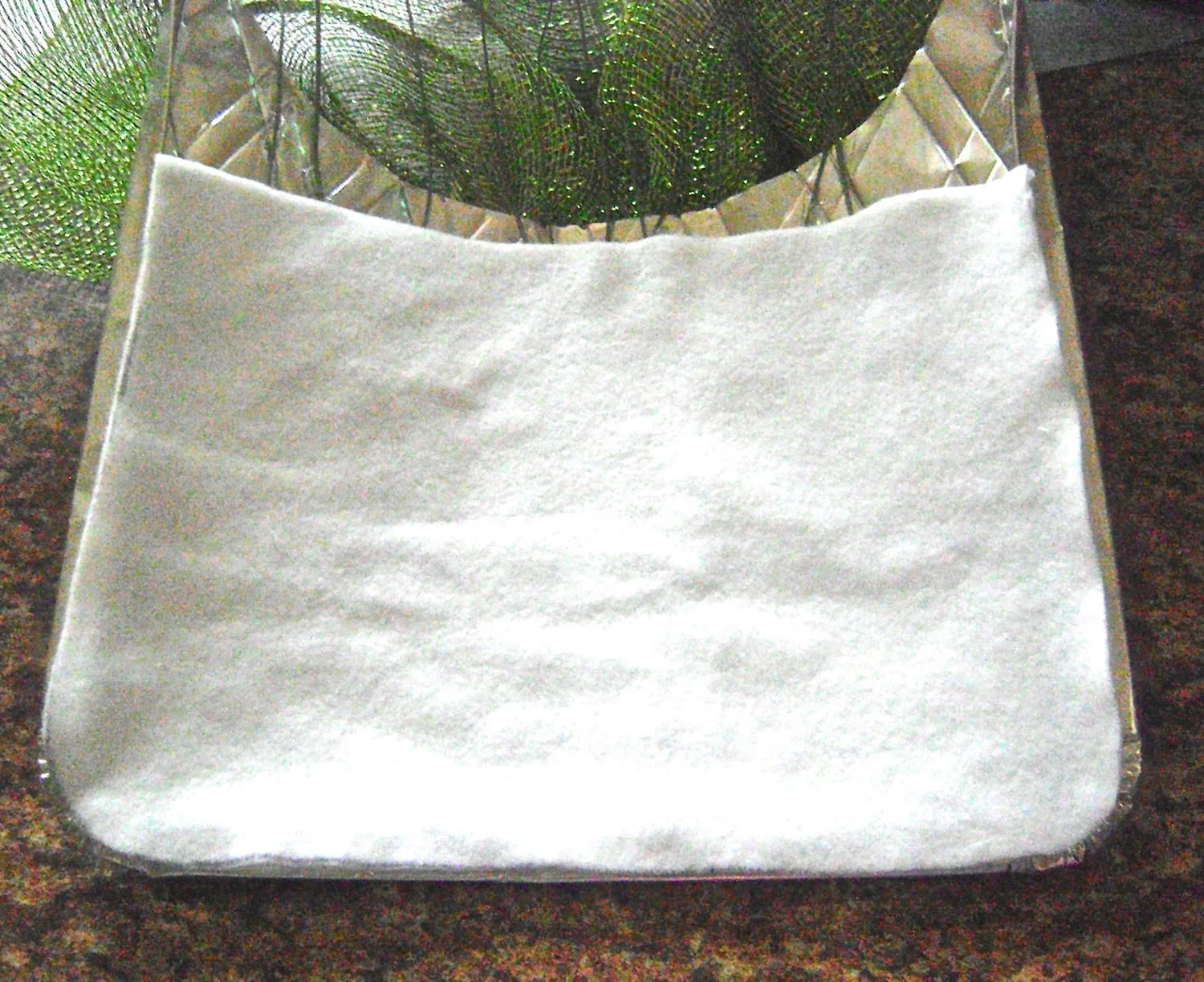 step 14 - Fold the edges of the foil flat and trace the shape of the bottom and sides to create a template. Use the template to cut a lining out fleece, felt, or other soft fabric. Hot glue the lining to the foil back. The fabric will prevent the foil from scraping the finish on your door.