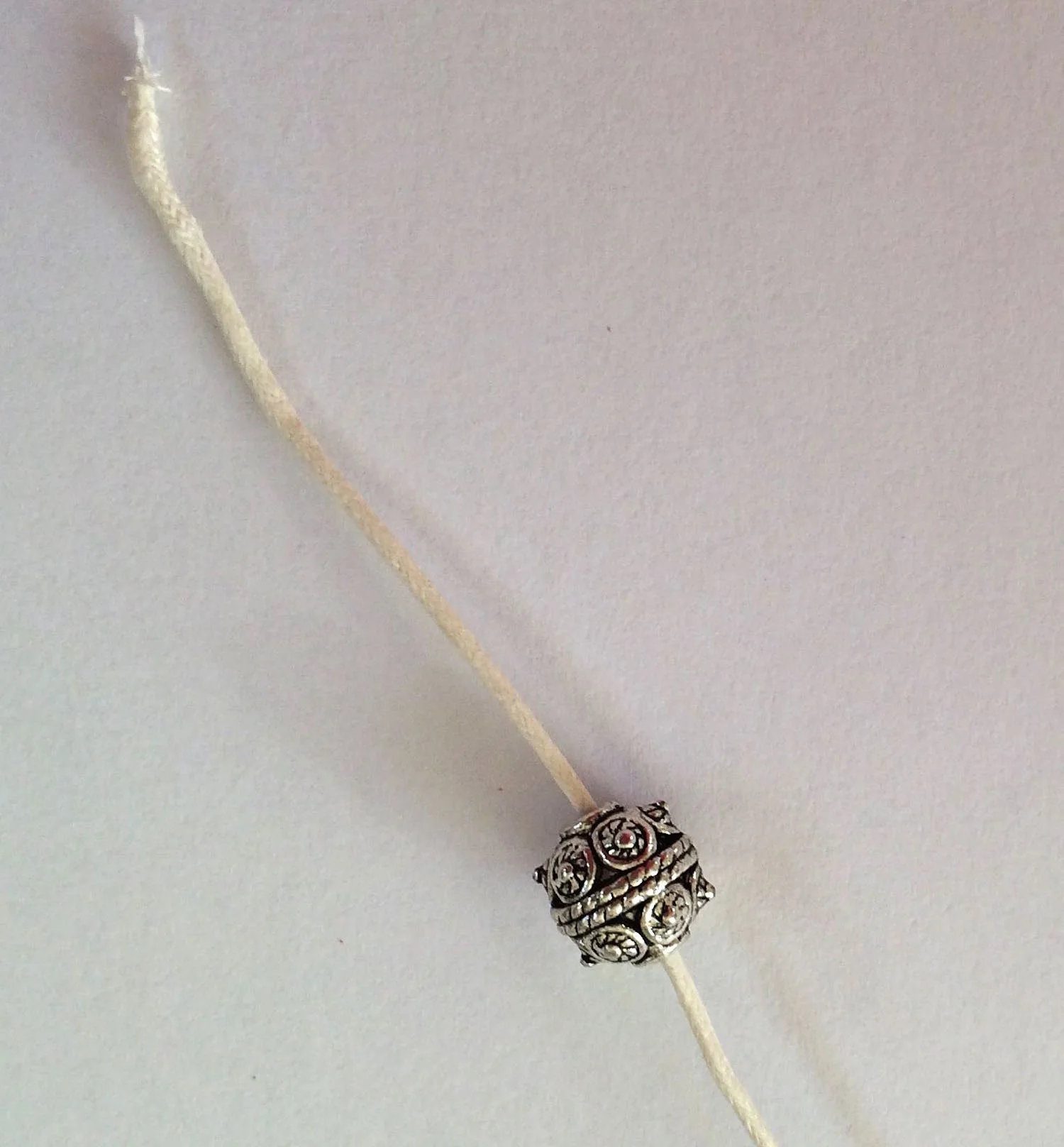 step 6 - Attach a decorative bead to the cord ends then tie a double knot. The beads will prevent the cord from slipping out of the mesh.
