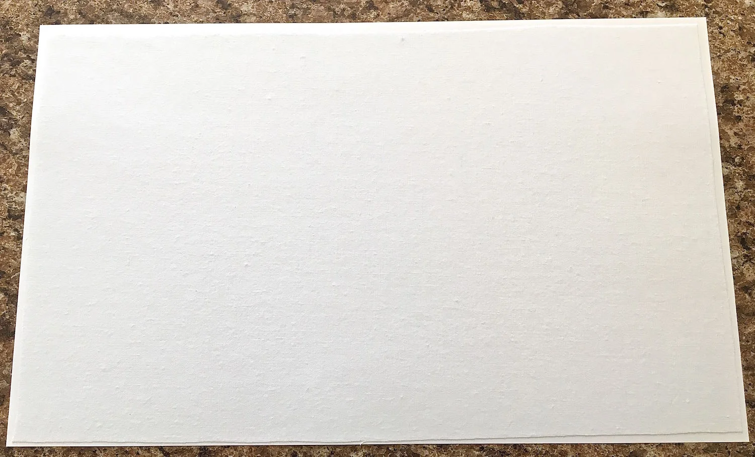 step 2 - Cut inside the line about .25” on all sides. Spray adhesive on the wrong side of the material. Press the fabric onto the card stock .25” away from the edges. Smooth out any bubbles.
