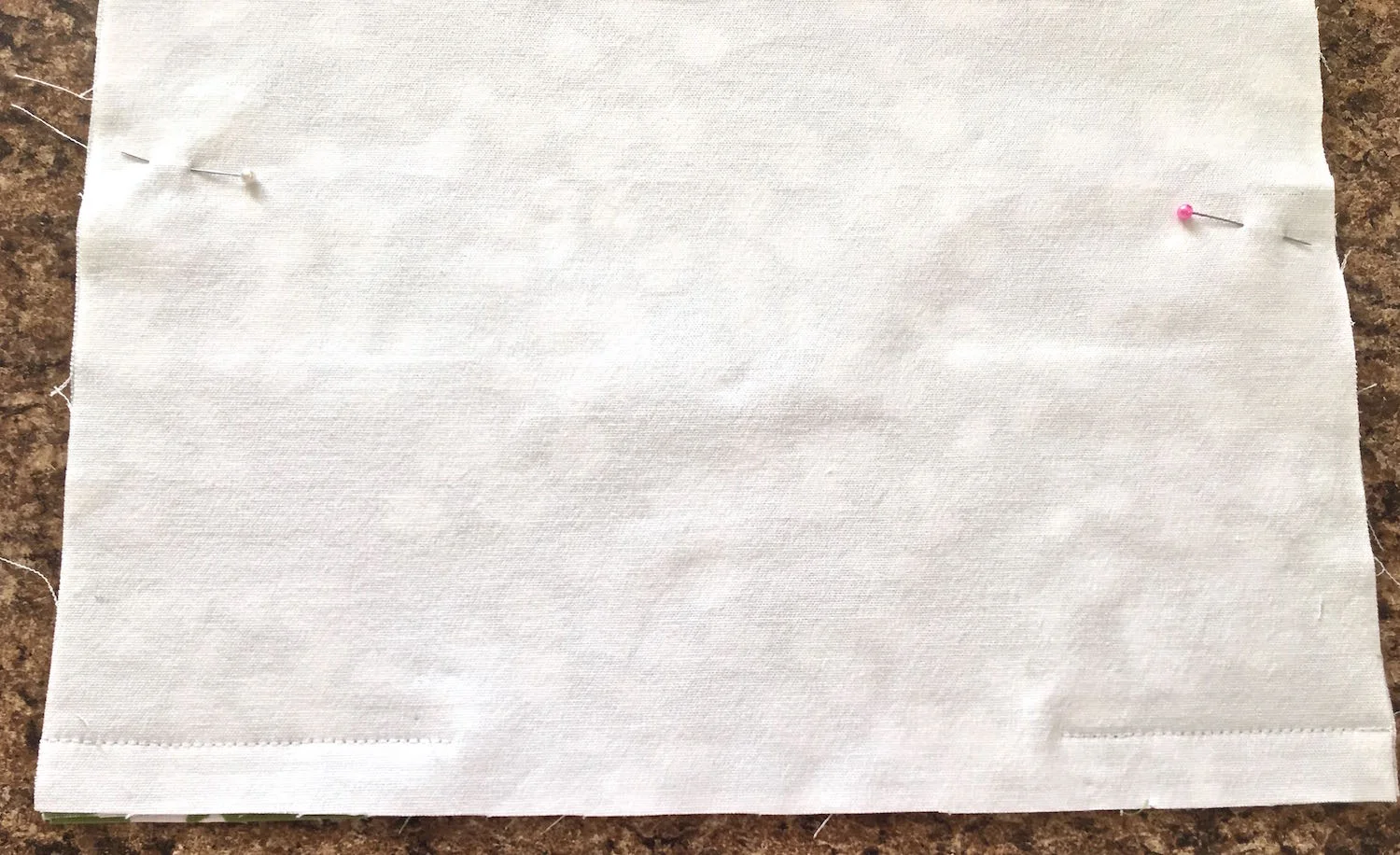 step 8 - Apply interfacing to the 14” x !4” floral fabric. Pin it to the same size lining piece to complete the back panel. Pin the front and back panels with right sides together. Stitch a 5/8” seam on the bottom edge for the zipper. Only sew 2” in from the sides leaving the middle open.