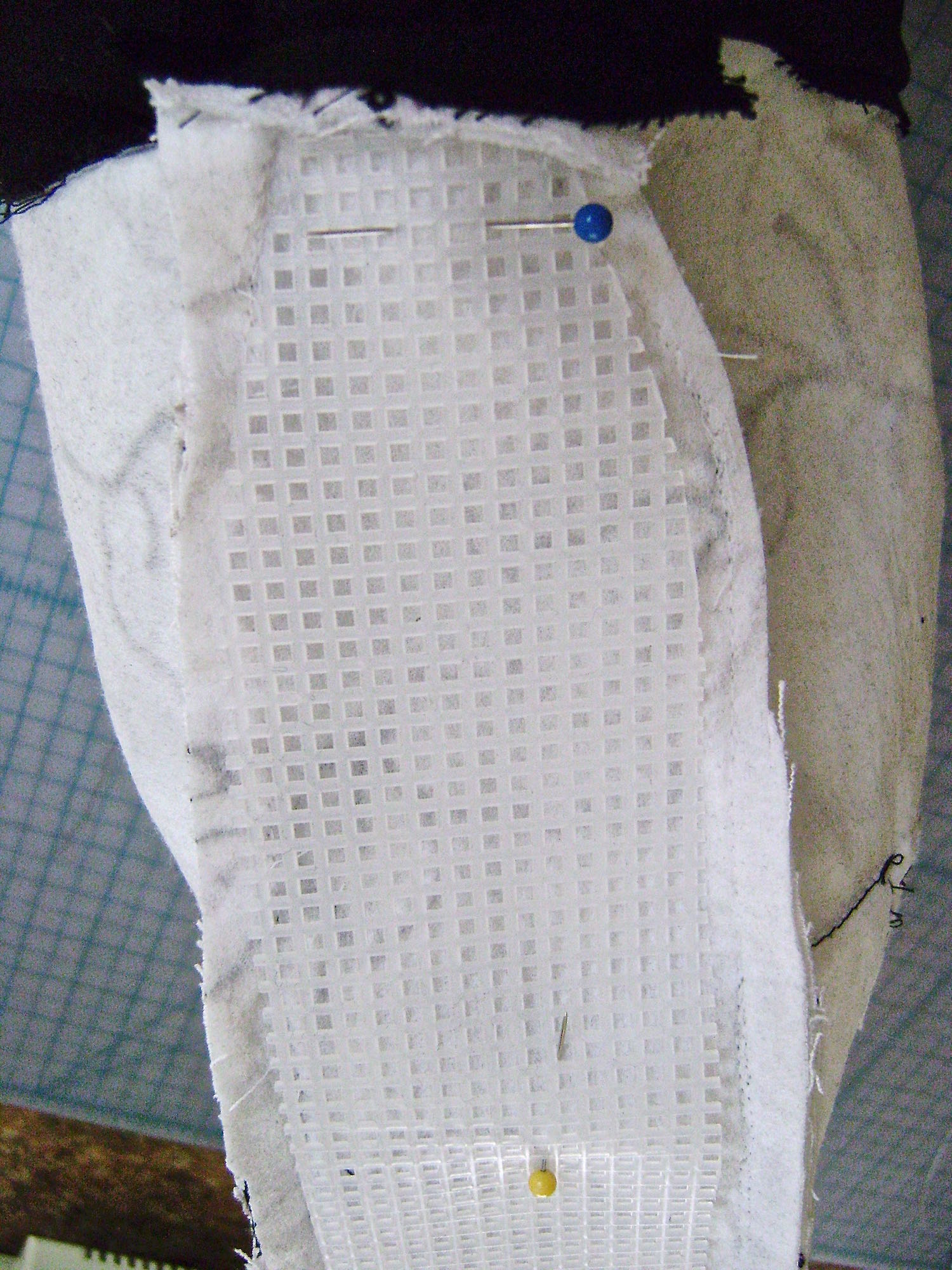 step 2 - Center the cardboard against the bottom of the bag. Pin the plastic gusset pieces up the sides. They should fit between the fabric gusset seams. Trim the plastic more if necessary. step 3 - Work down one side, across the bottom and up the other side, securing the plastic to the fabric every few inches with tacking stitches.